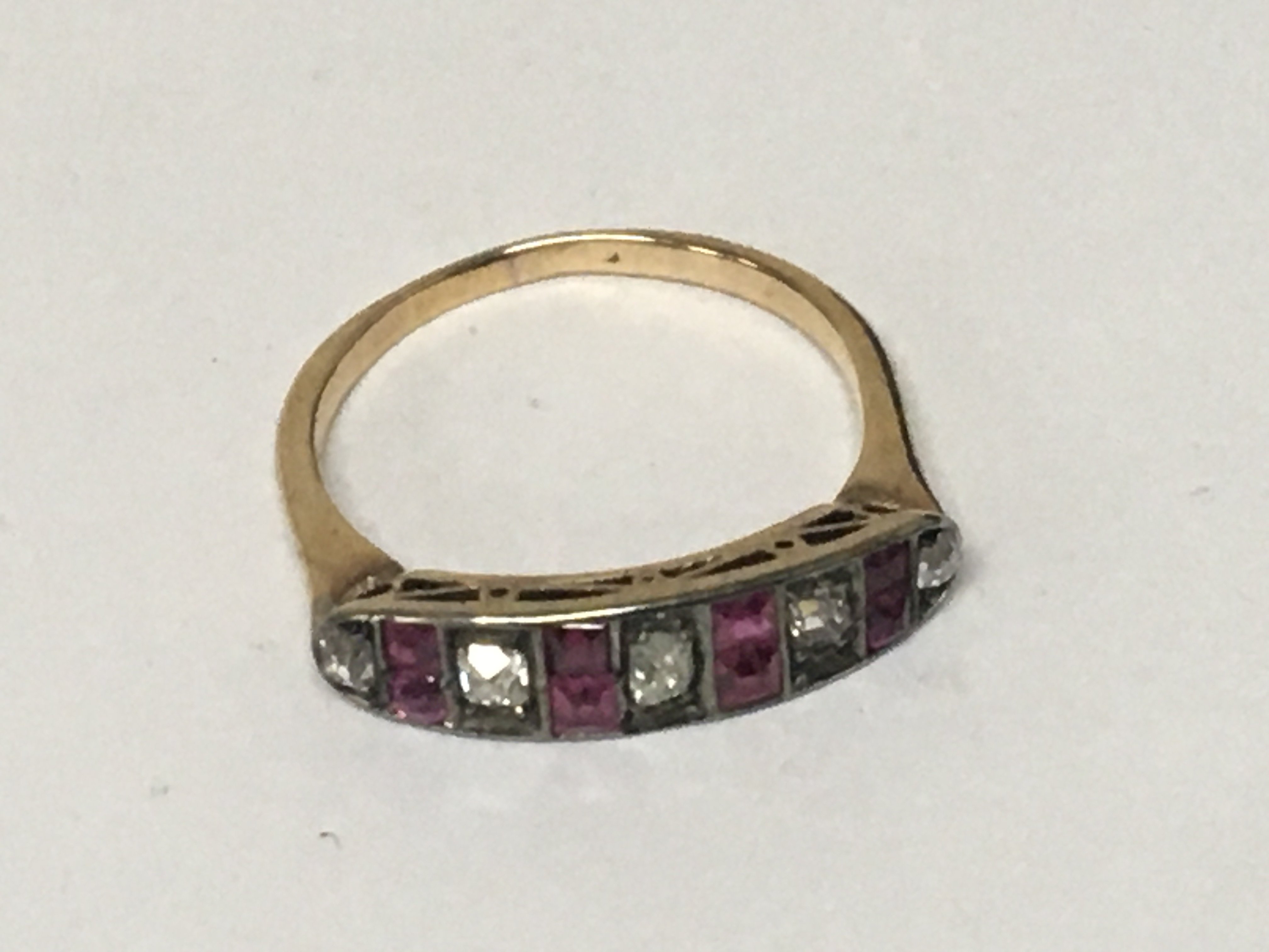 An unmarked worn marks gold ring set with ruby coloured stones and white stones weight