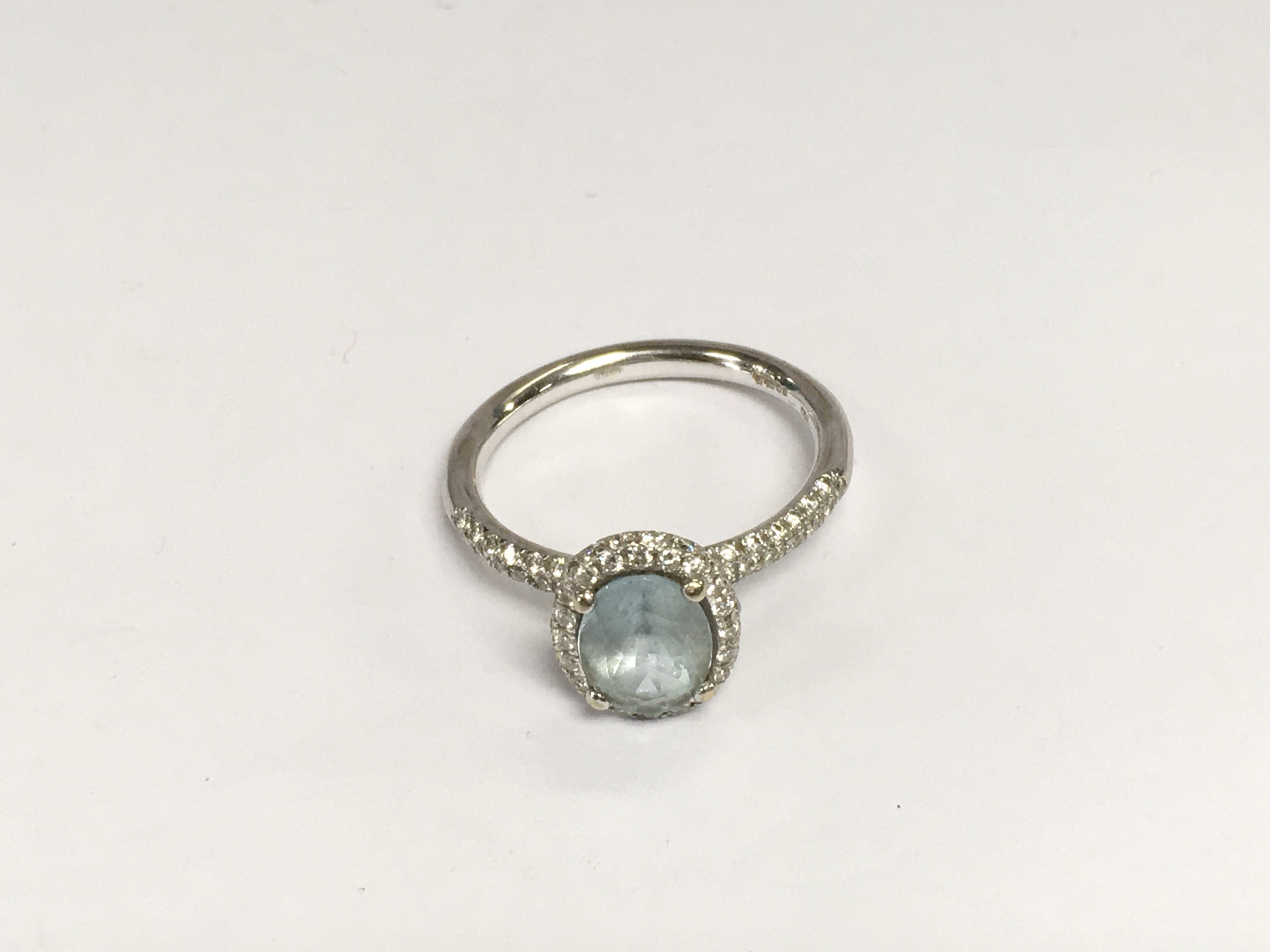 An 18ct white gold ring set with a central aquamarine flanked by diamonds, approx 5.4g and approx size R-S. Shipping category A.