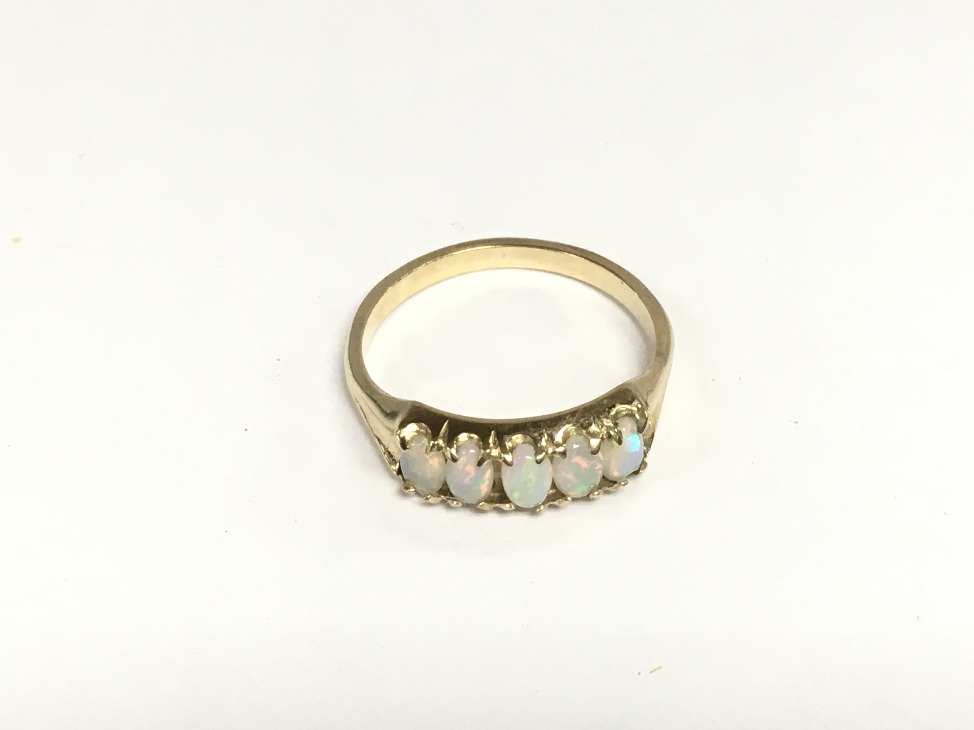An unmarked gold ring set with five opals, approx 2.8g and approx size R-S. Shipping category A.