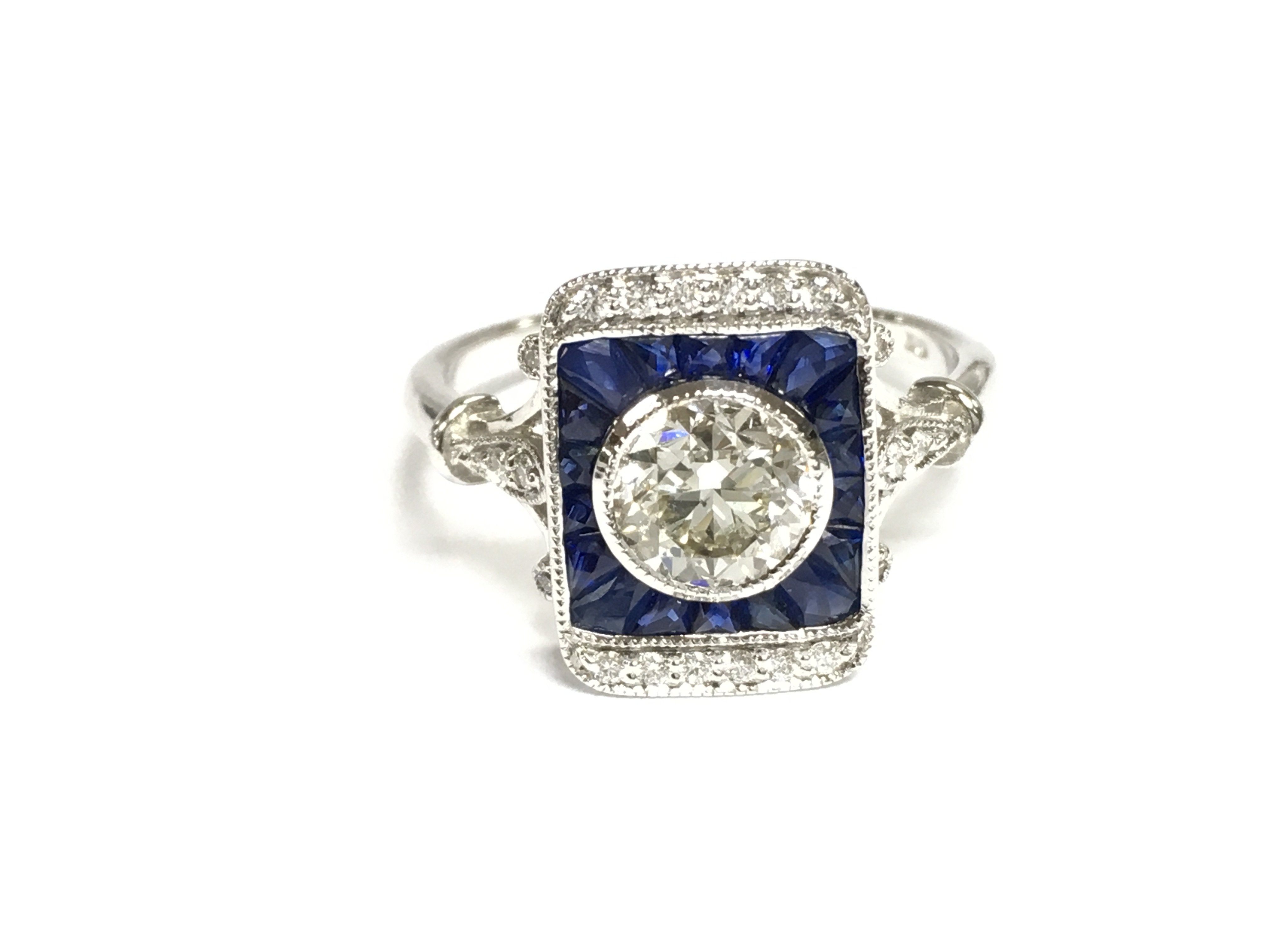 18ct white gold target style ring set with central diamond surrounded by mixed cut sapphires and further diamonds. Central diamond is 1.01ct. Size N 1/2