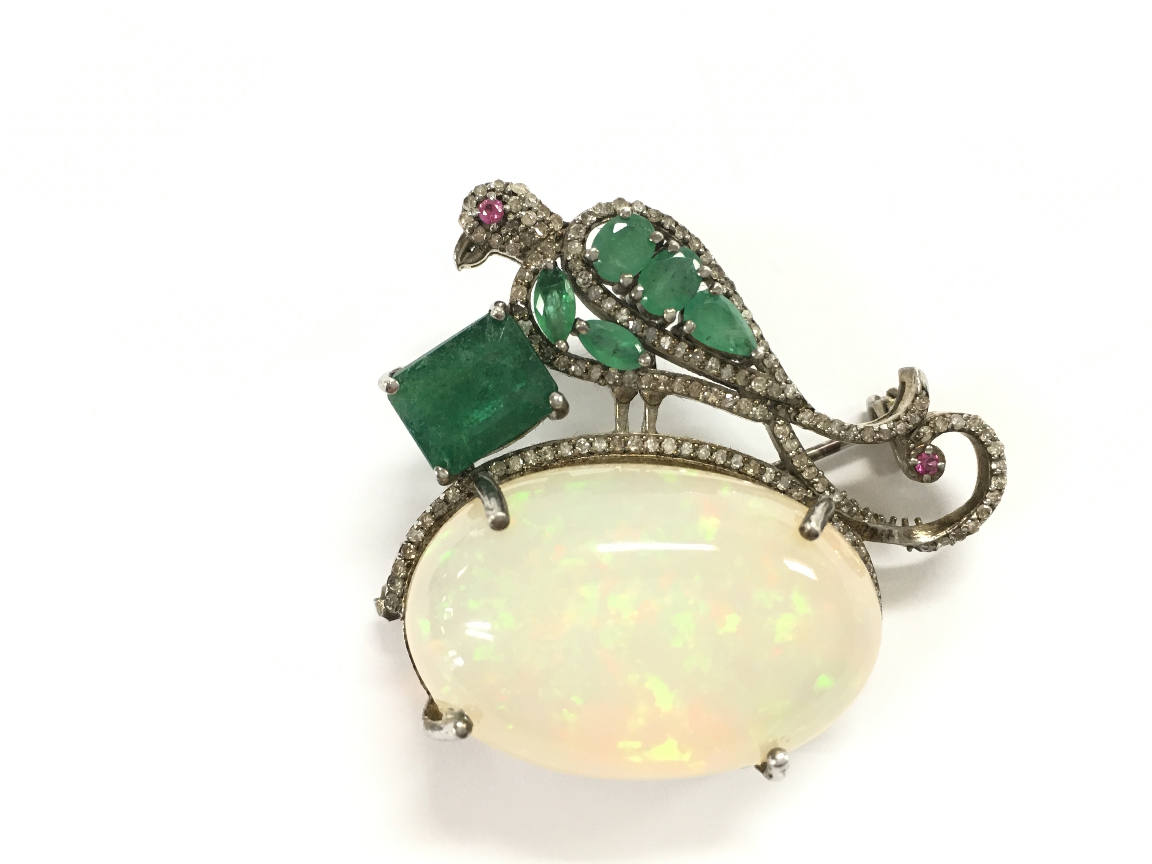 Bird of paradise brooch - pendant in silver set with a large cabochon oval opal ruby eyes and emerald and diamonds. Opal 26.18ct emeralds 3.16ct and diamonds 0.69ct all approximately.