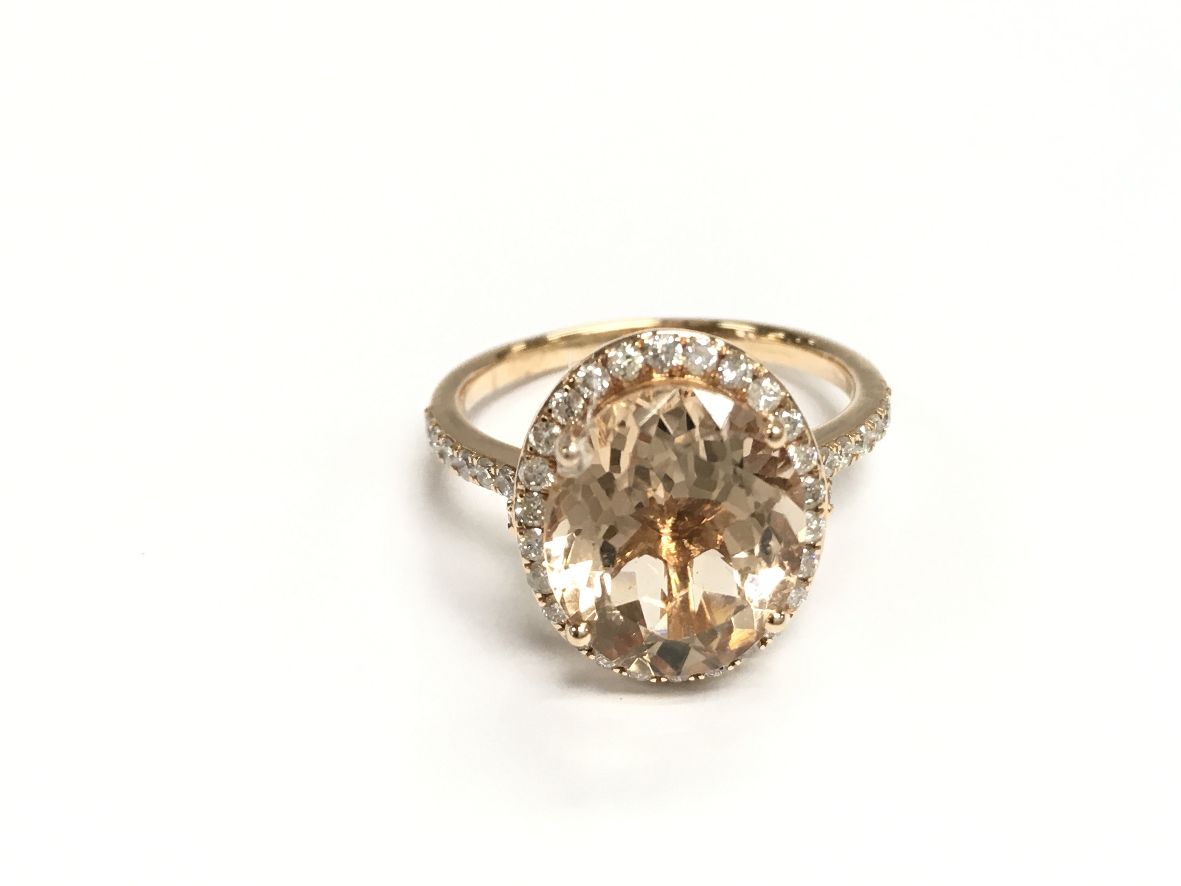 An 18ct rose gold ring set with an oval morganite surrounded by a halo of diamonds with diamond shoulders. Morganite 4.26ct and 0.49ct diamonds Approx and size P