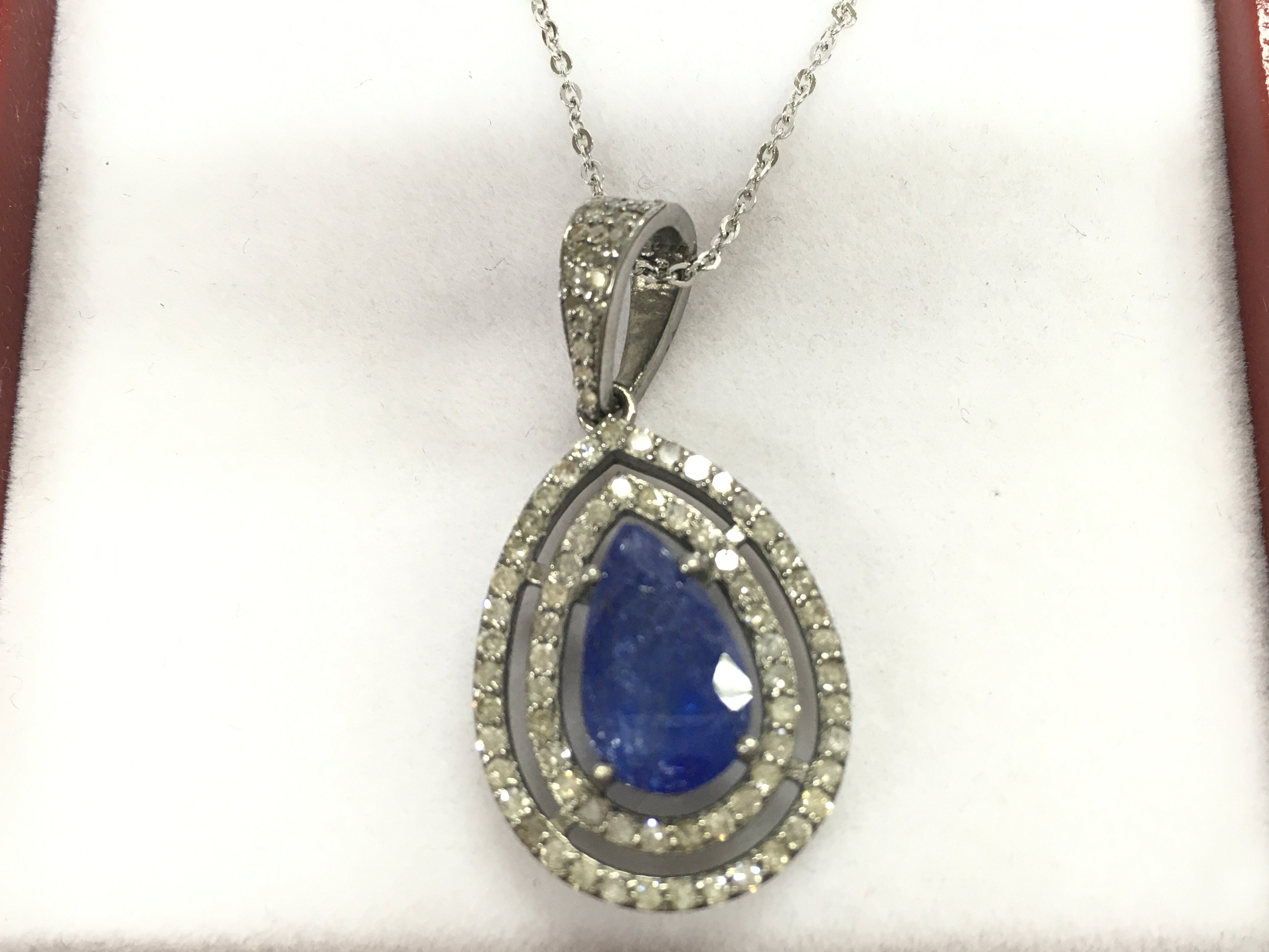 A silver pendant with pear shaped tanzanite surrounded by diamonds on a silver chain. Tanzanite 3.61ct and diamonds 0.71ct approximately.