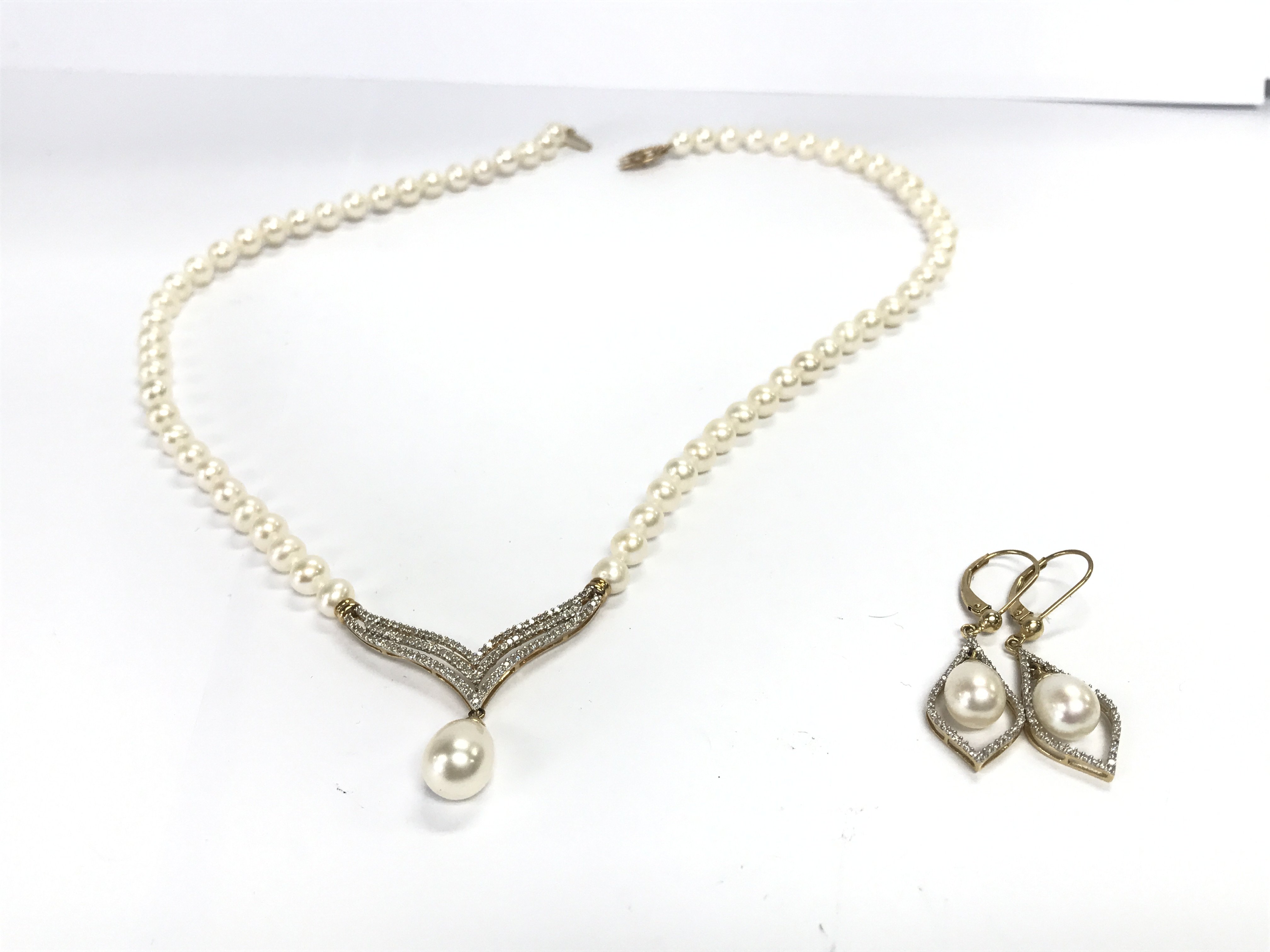 A pair of 14k gold pearl earrings and a conforming 14k gold pearl necklace.