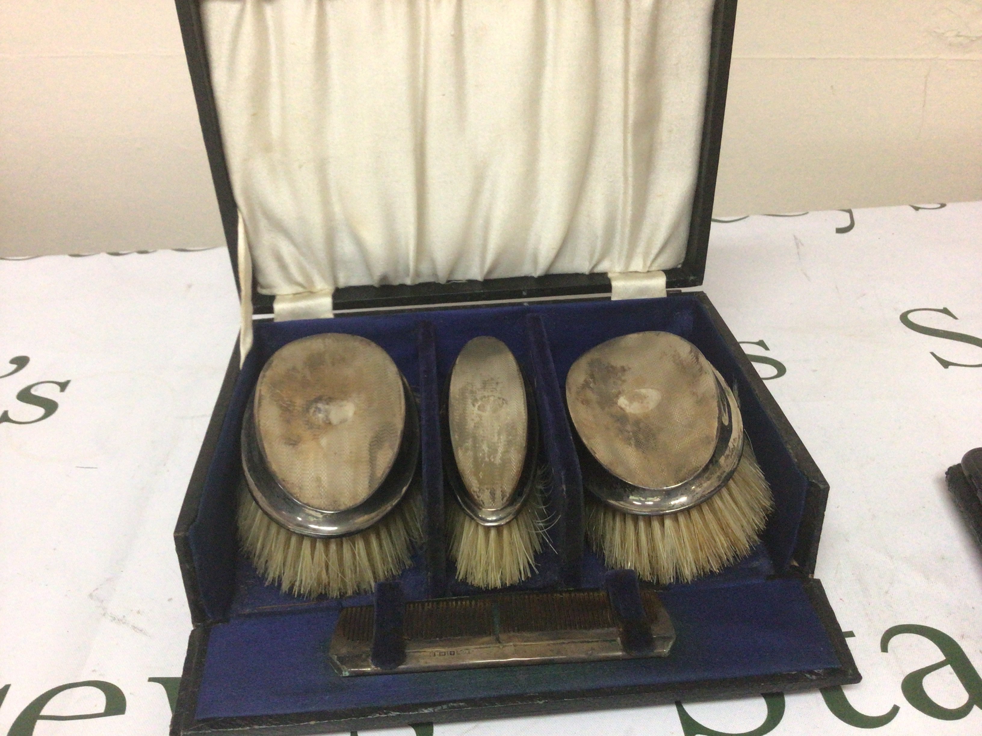 A cased set of three silver mounted brushes with a comb in a fitted case.