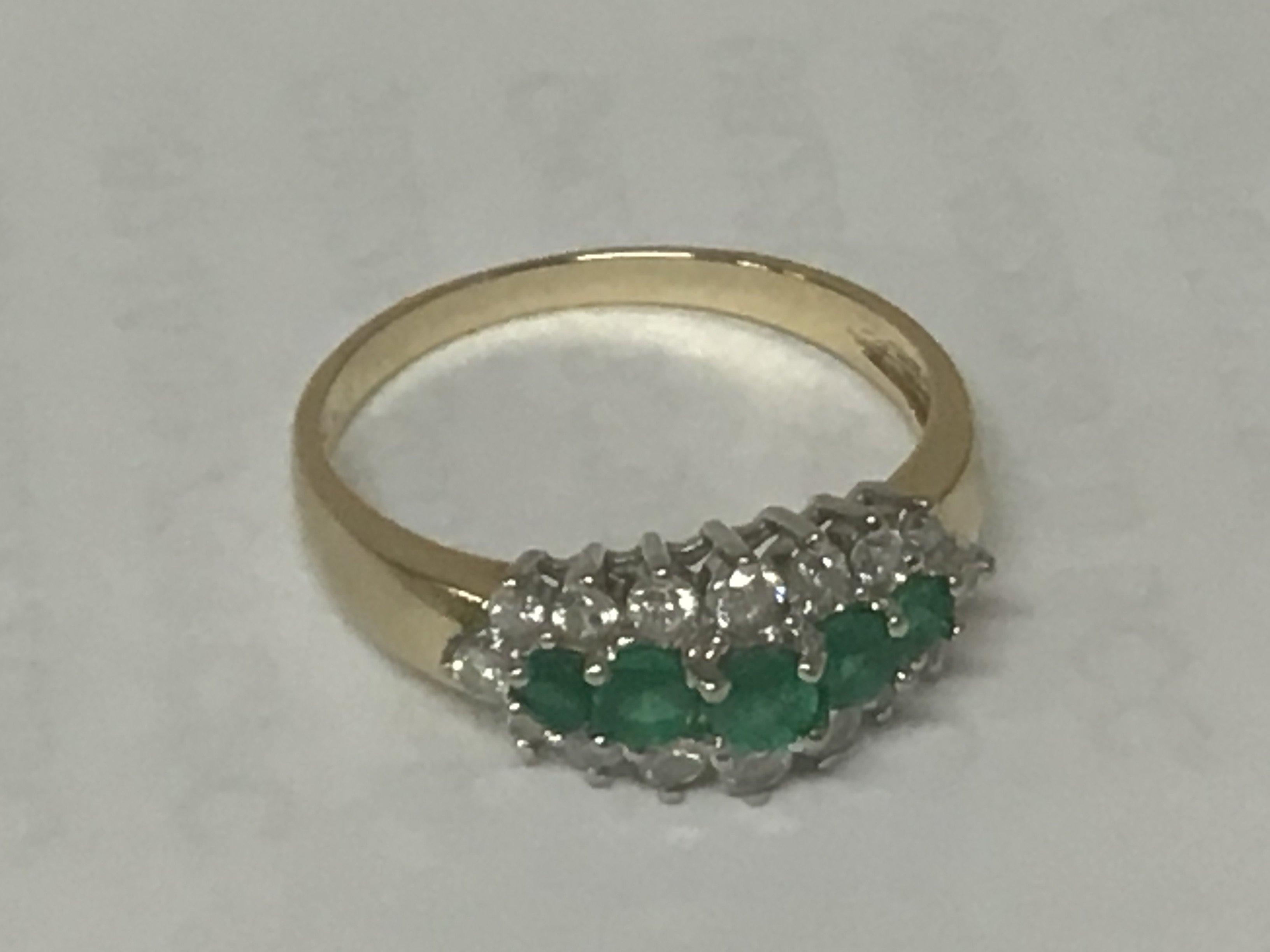 A 14carat gold ring set with emerald and small diamonds and emeralds. 2.5g approximately.