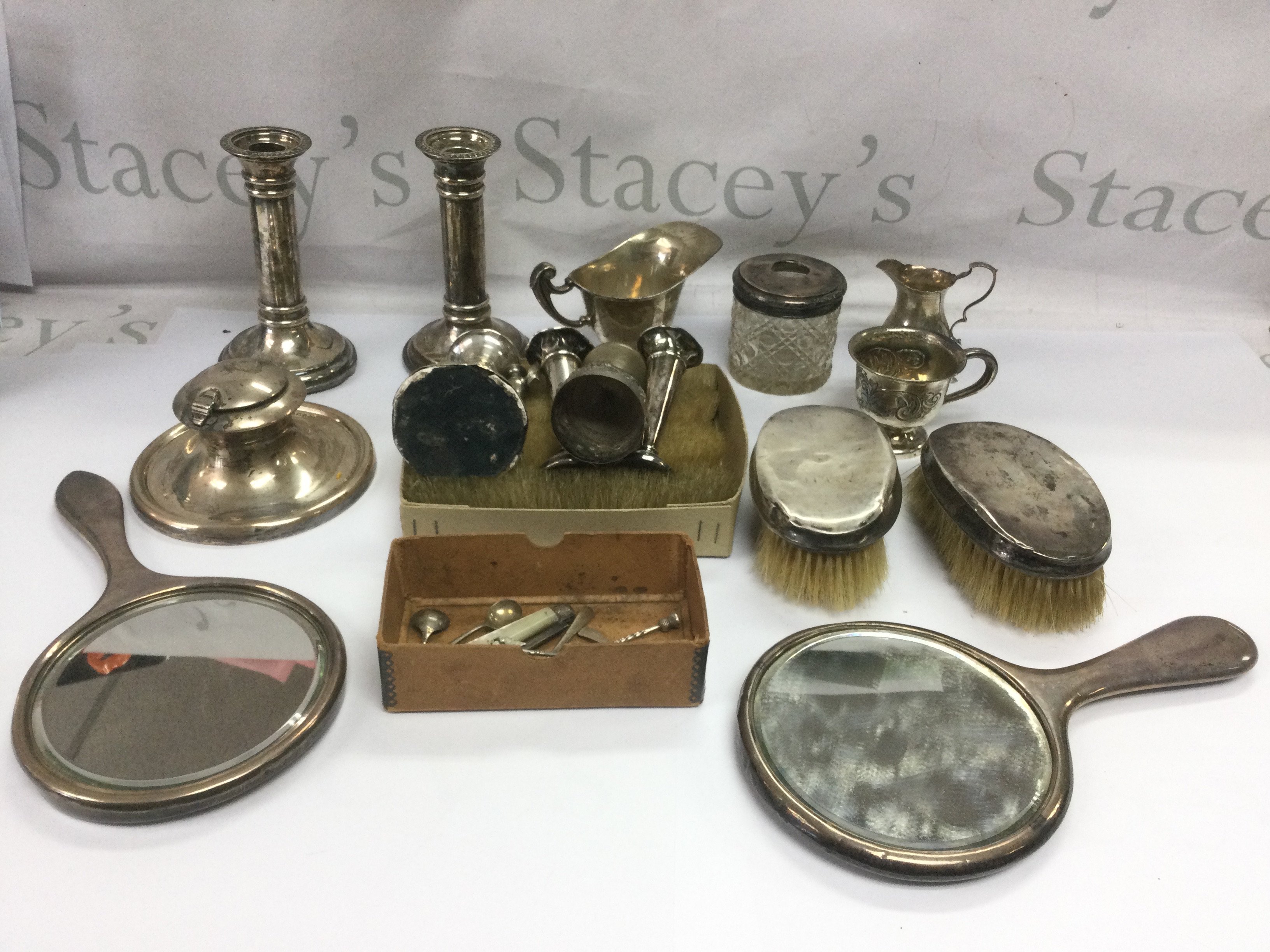 A collection of ilver items comprising a pair of candlesticks, two hand mirrors, capstan inkwell etc. Shipping category D.