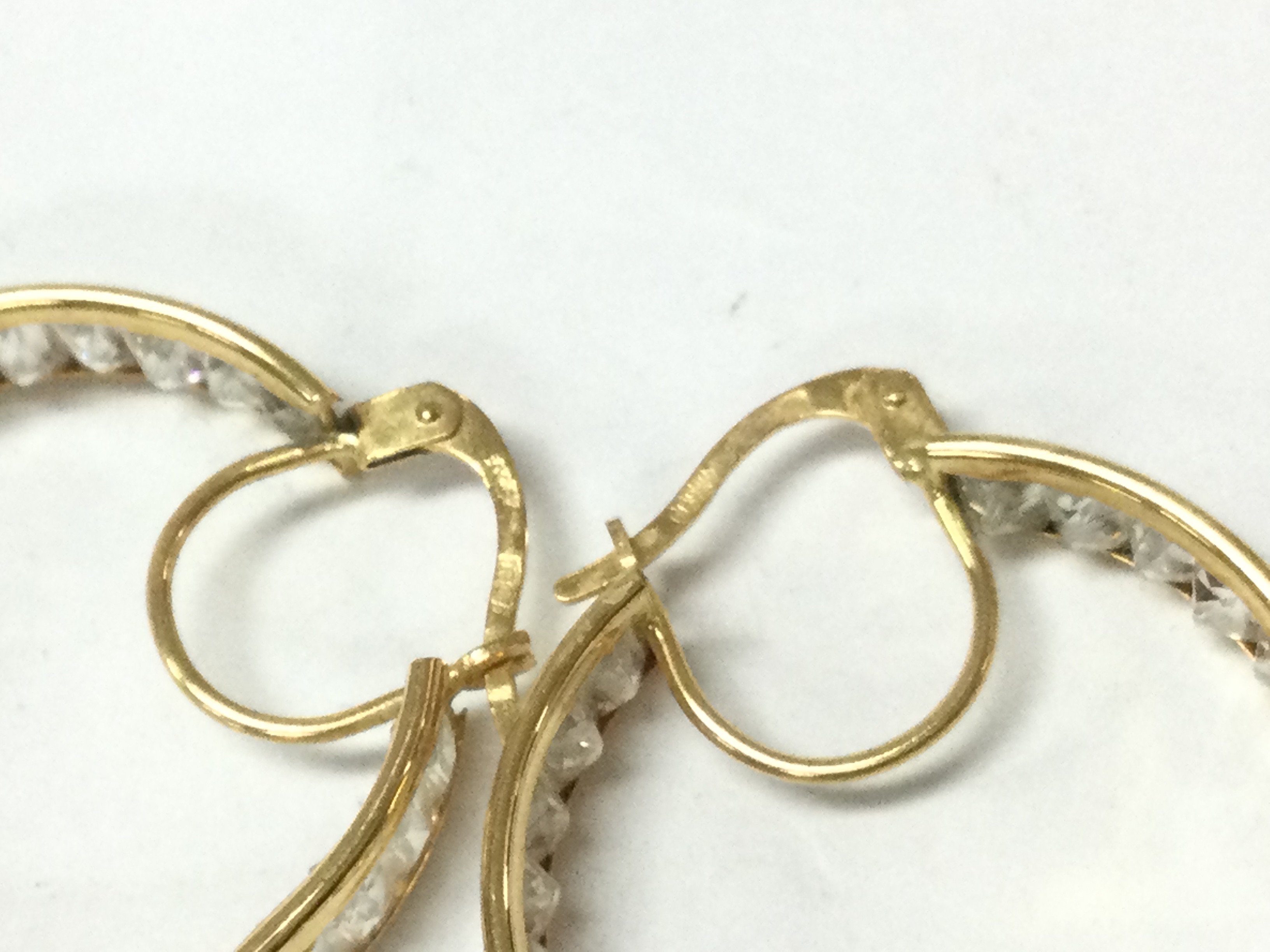 An unhallmarked high grade gold pair of hoop earrings set with white stones. 6.02g Postage B