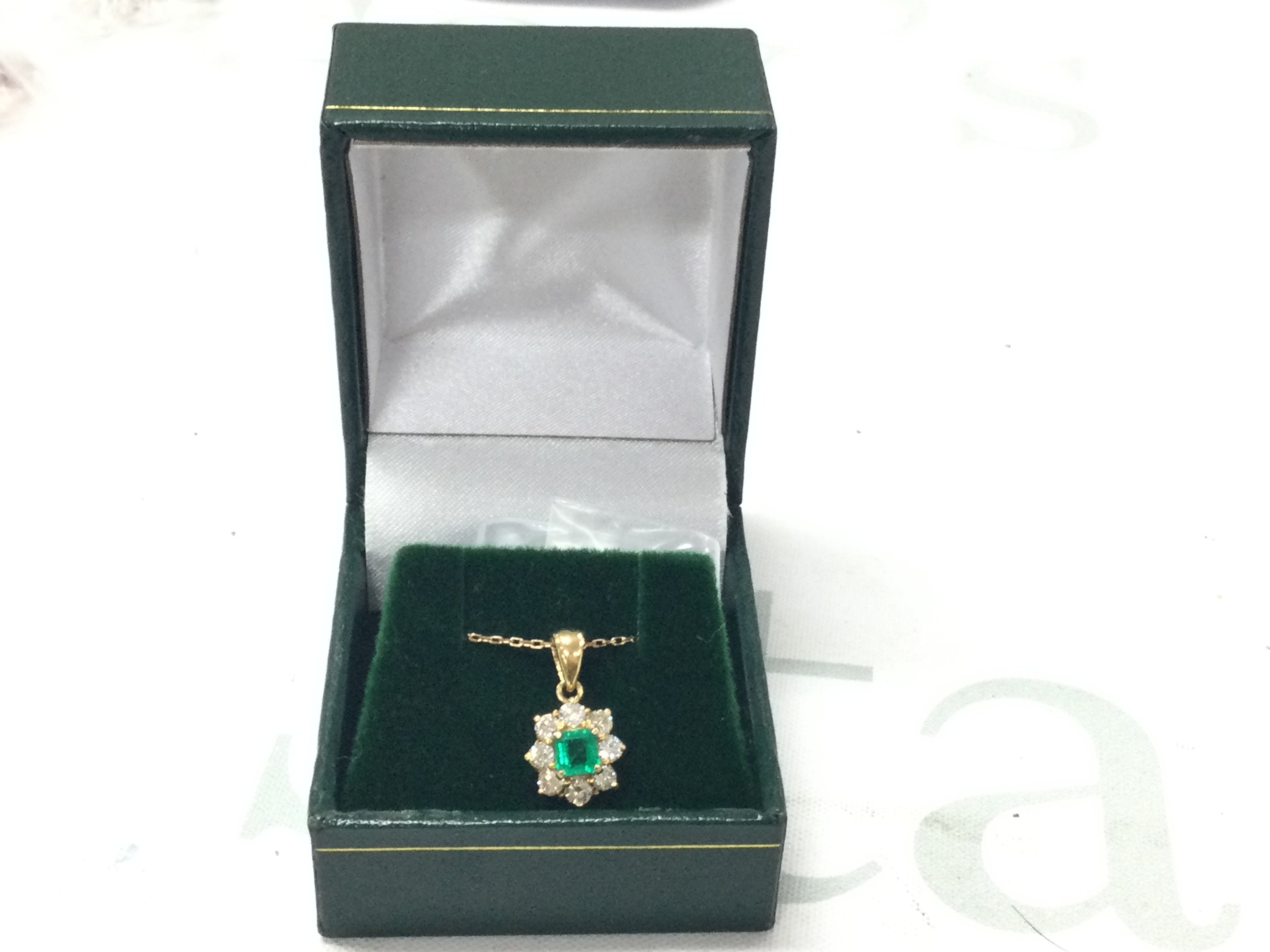 18ct yellow gold pendant set with a square step-cut emerald surround by RBC diamonds, on an 18ct yellow gold chain. Emeralds 0.34ct, Diamonds 0.52ct