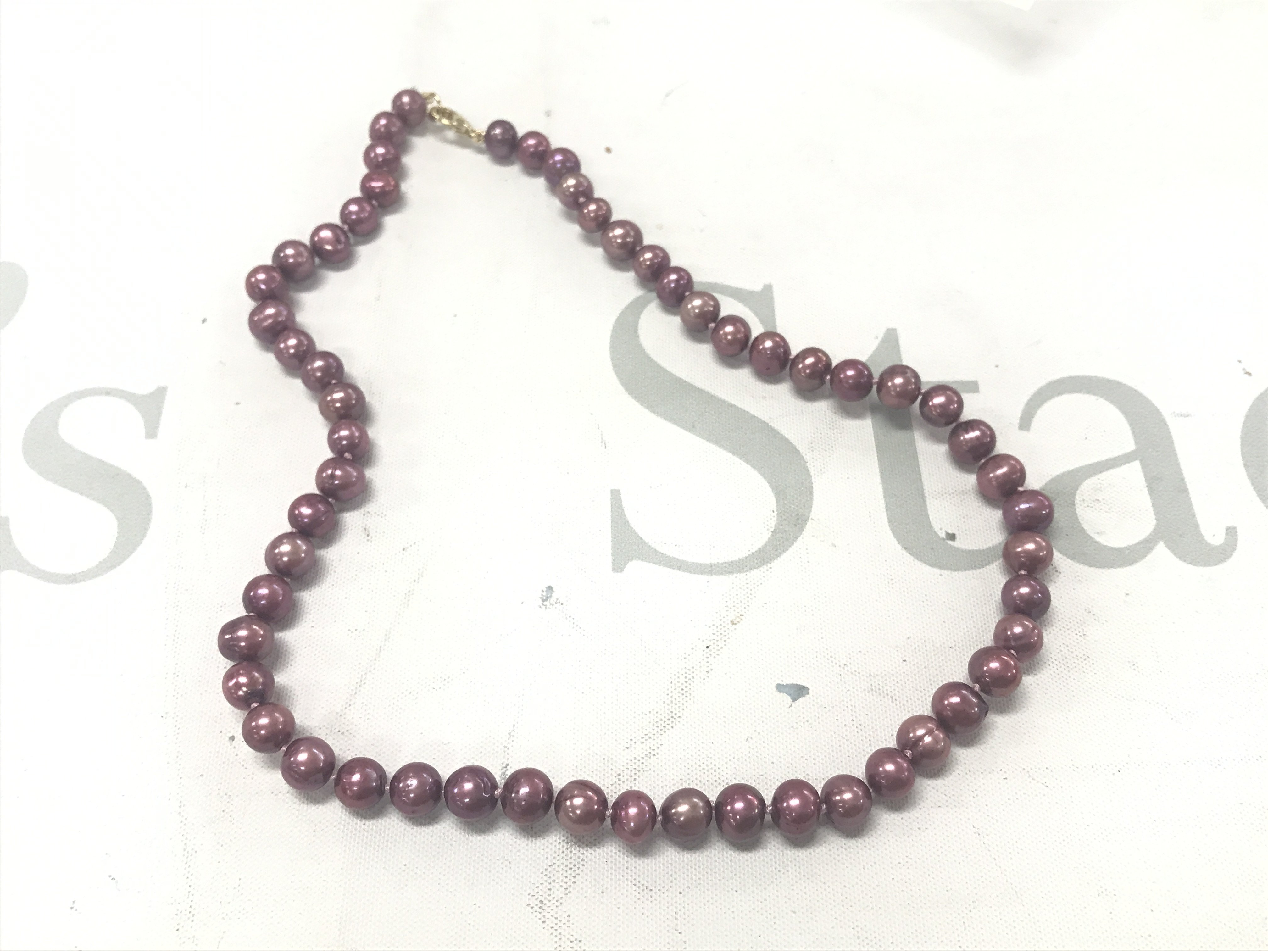 Pinkish purple cultured pearl-strung necklace with gold-plated lobster claw clasp.