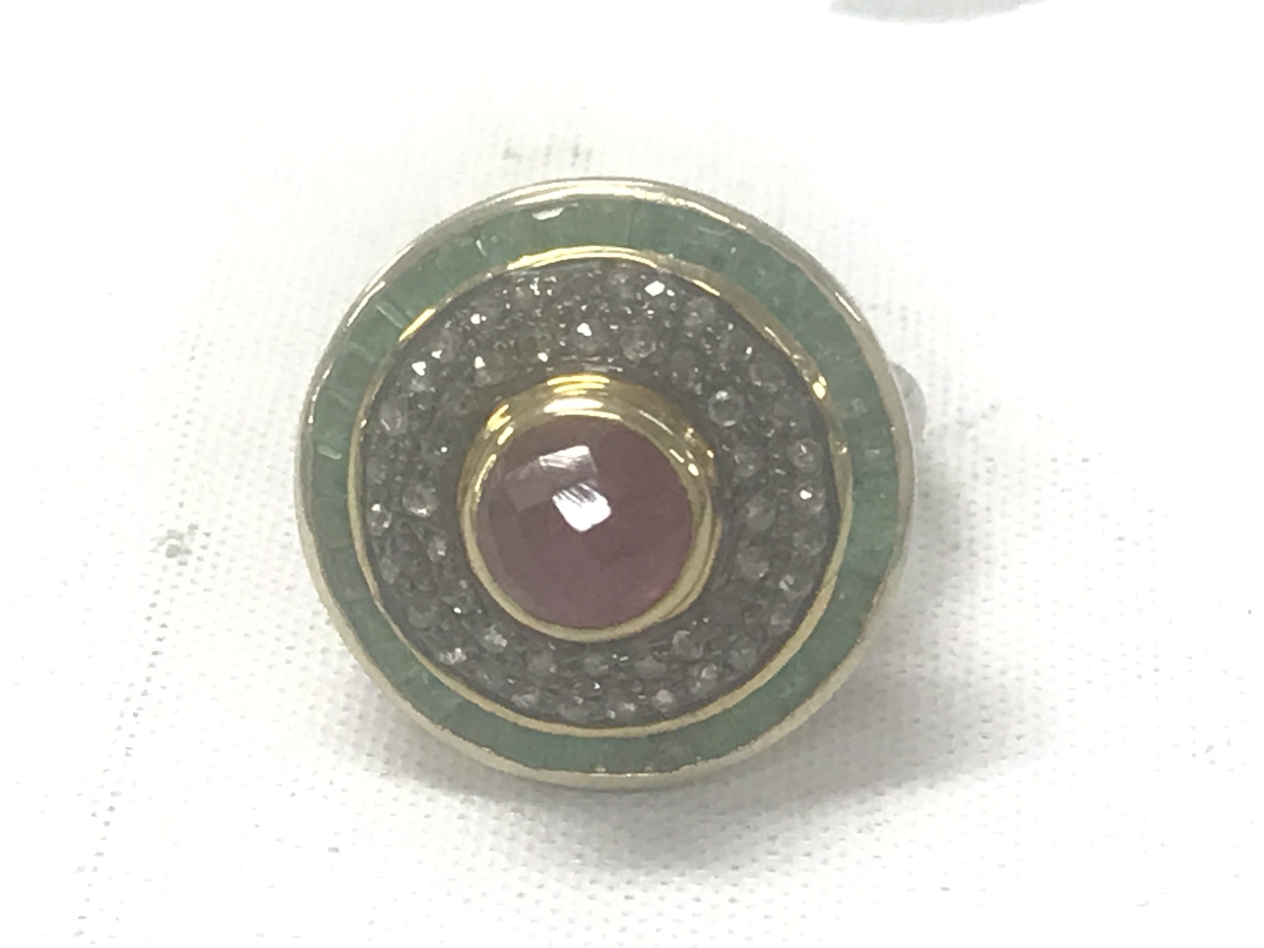 Large target style dress ring in silver and silver-gilt set with a round domed checkerboard pink tourmaline surrounded by rose cut diamonds, and an outer halo of square-cut emeralds. Tourmaline 1.88ct. Emeralds 1.29ct. Diamonds 0.63ct.