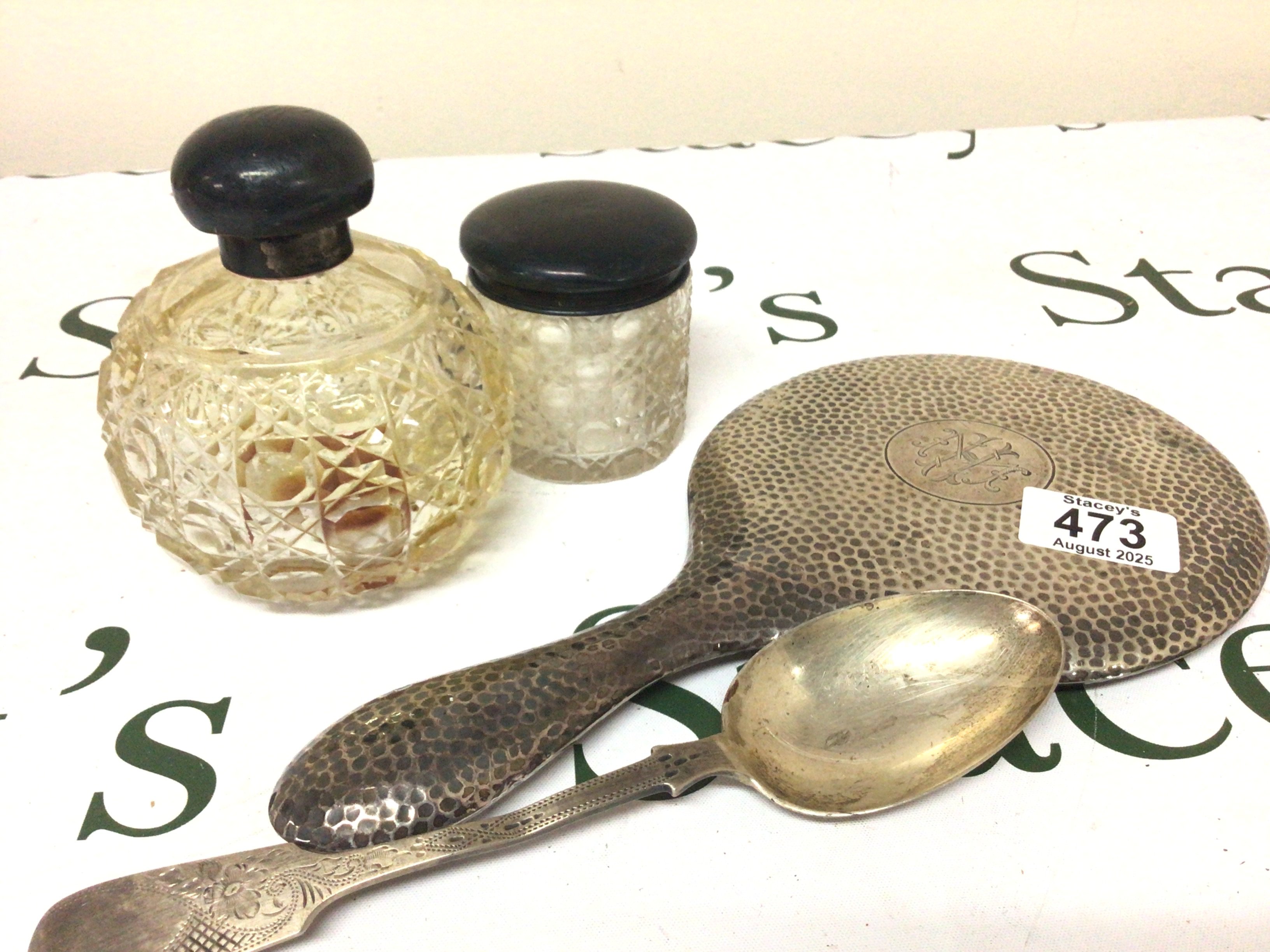 A silver backed mirror silver spoon silver mounted cut glass scent bottle and a tidy jar.