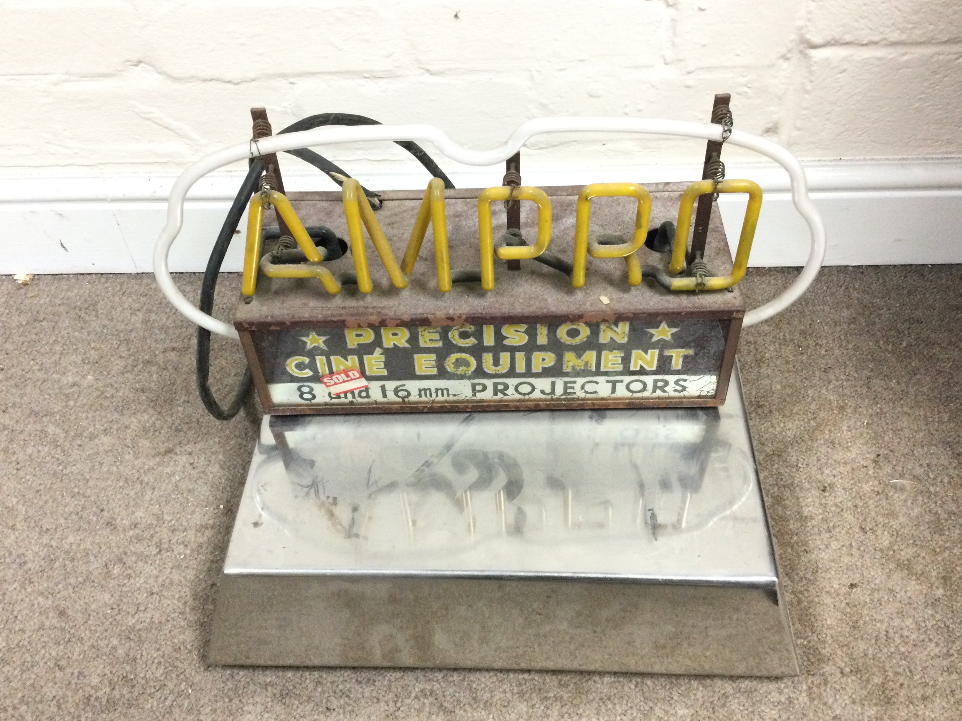 An AMPRO neon sign on chrome stand. Overall size is approximately 18 x 16 inches
