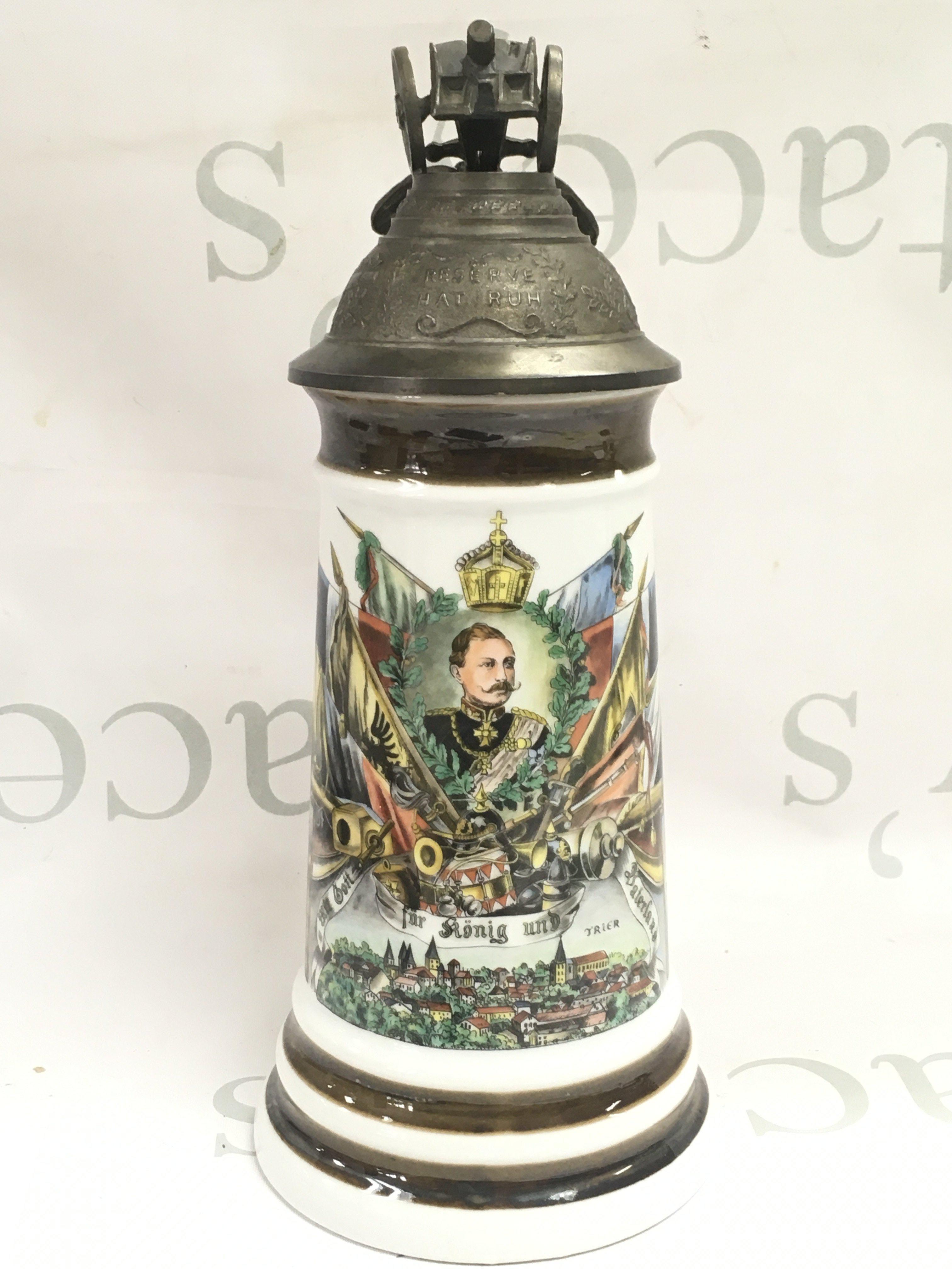 A German decorated stein with emblems of militaria and empower, the metal lid decorated with small cannon and eagle. 27cm tall. This lot cannot be posted