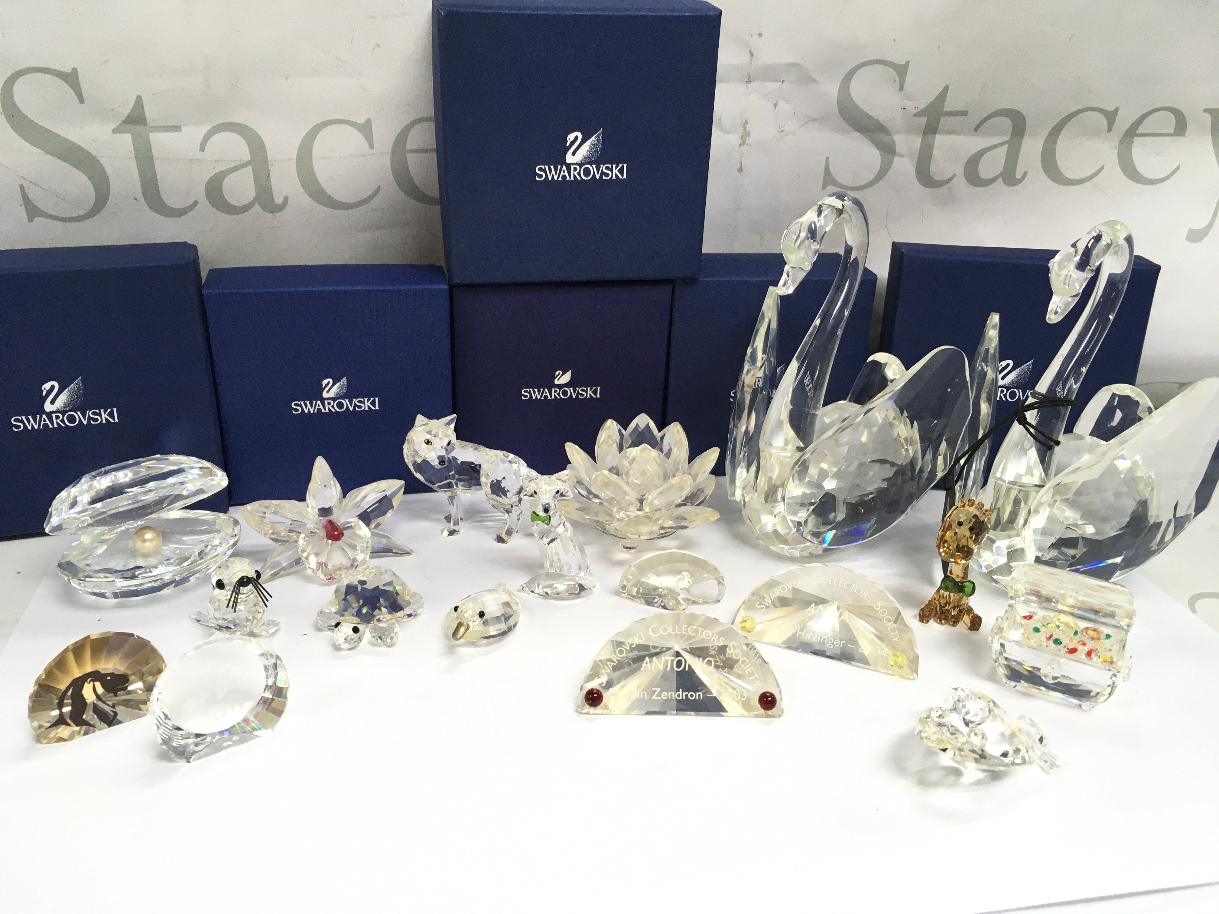A collection of Swarovski crystal glass figures including Shell with pearl, Orchard pink, Wolf, Artic fox, water lily, Treasure chest etc. some boxed and also Julien Macdonald swan figures. This lot cannot be posted