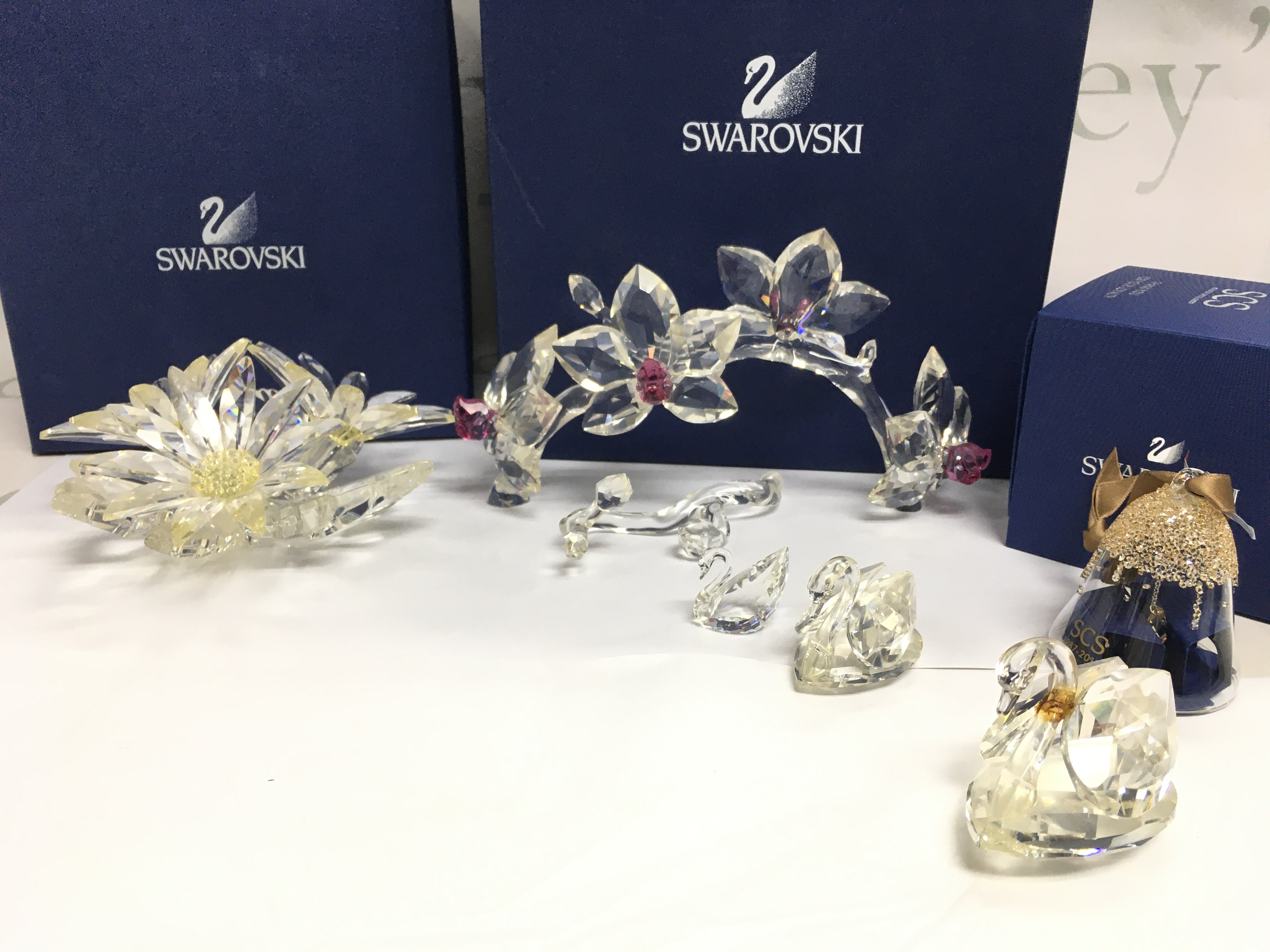 A collection of Swarovski including boxed Orchids on vine ( part needs re gluing ) , Maxi Flower, Christmas bell ornament, swans . This lot cannot be posted