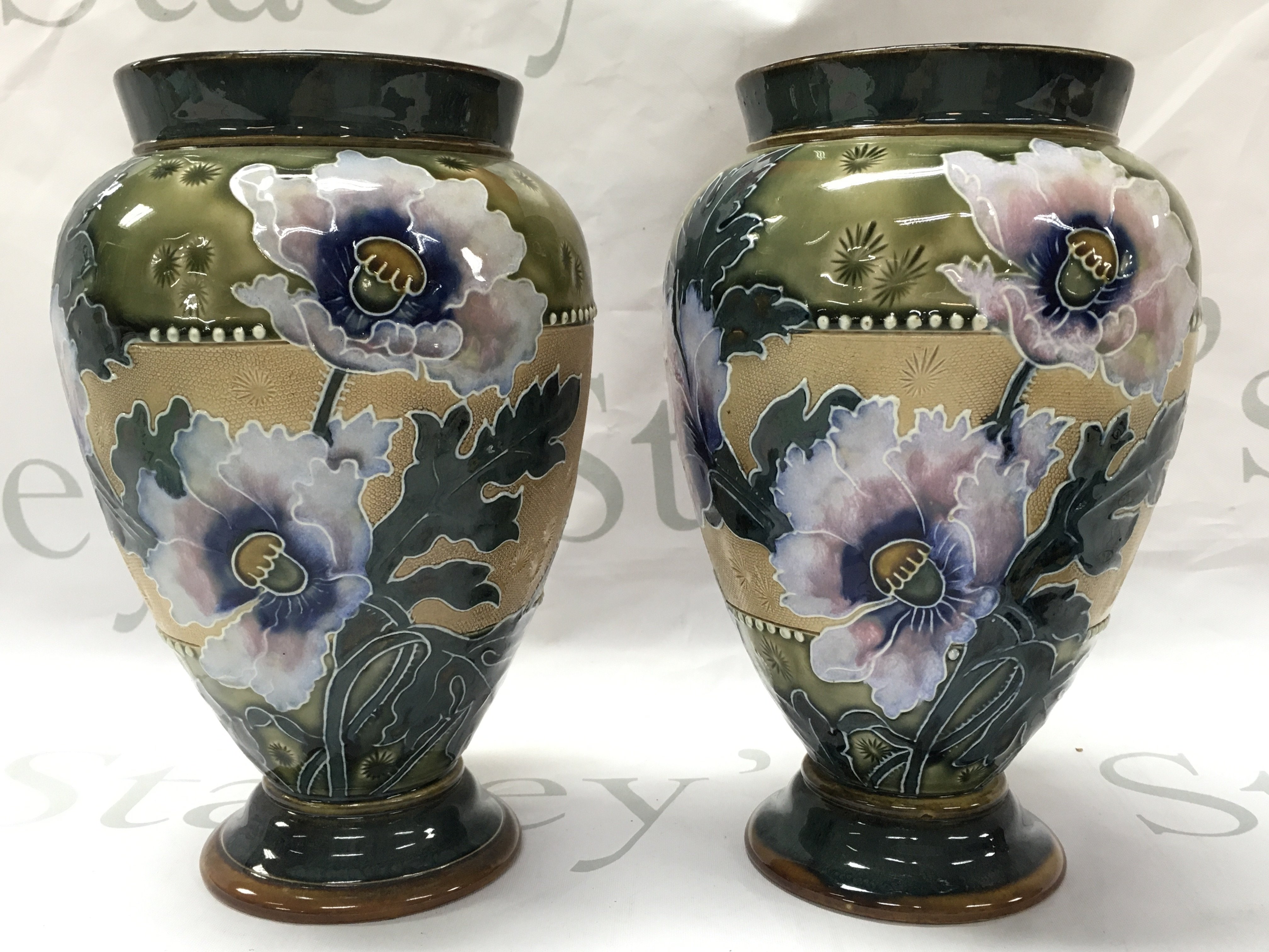 A pair of Doulton Lambeth vases , marked to the base . 21cm tall. This lot cannot be posted