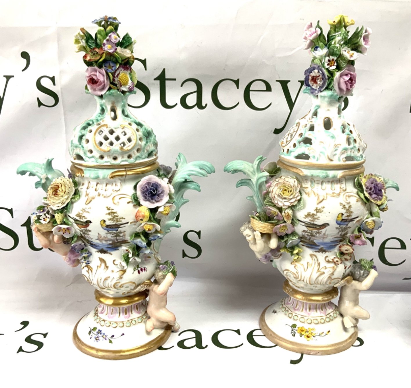 A pair of 19th Century German porcelain pot pourri vases and covers with cherub and floral decoration. 36cm. (Some areas of damage).