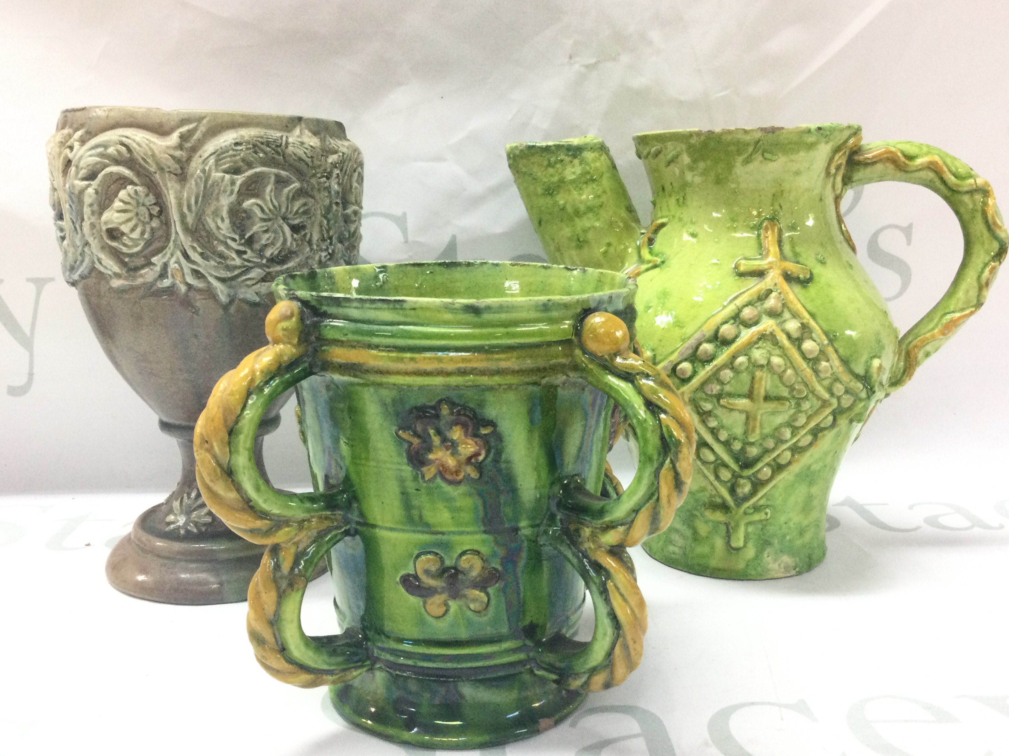 Three Castle Headingham pottery items including green and yellow glazed four handled jug and other jug and a goblet shaped vase . Tallest 18cm. This lot cannot be posted
