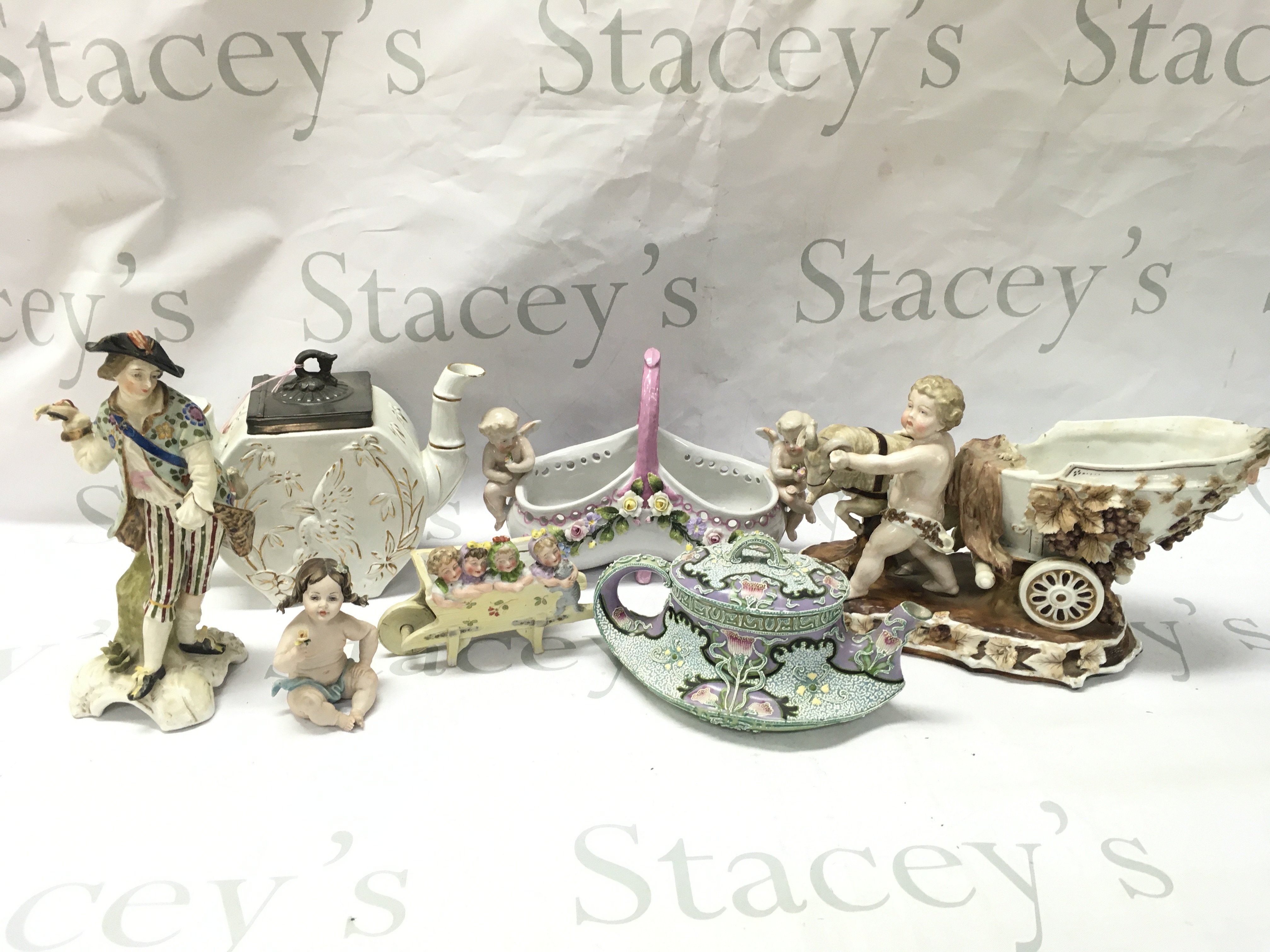 A Collection of early 20th century ceramics including an Crane design teapot, Capodimonte small girl figure , Italian Depose cherub basket , German Putti with chariot and goat figure group. This lot cannot be posted