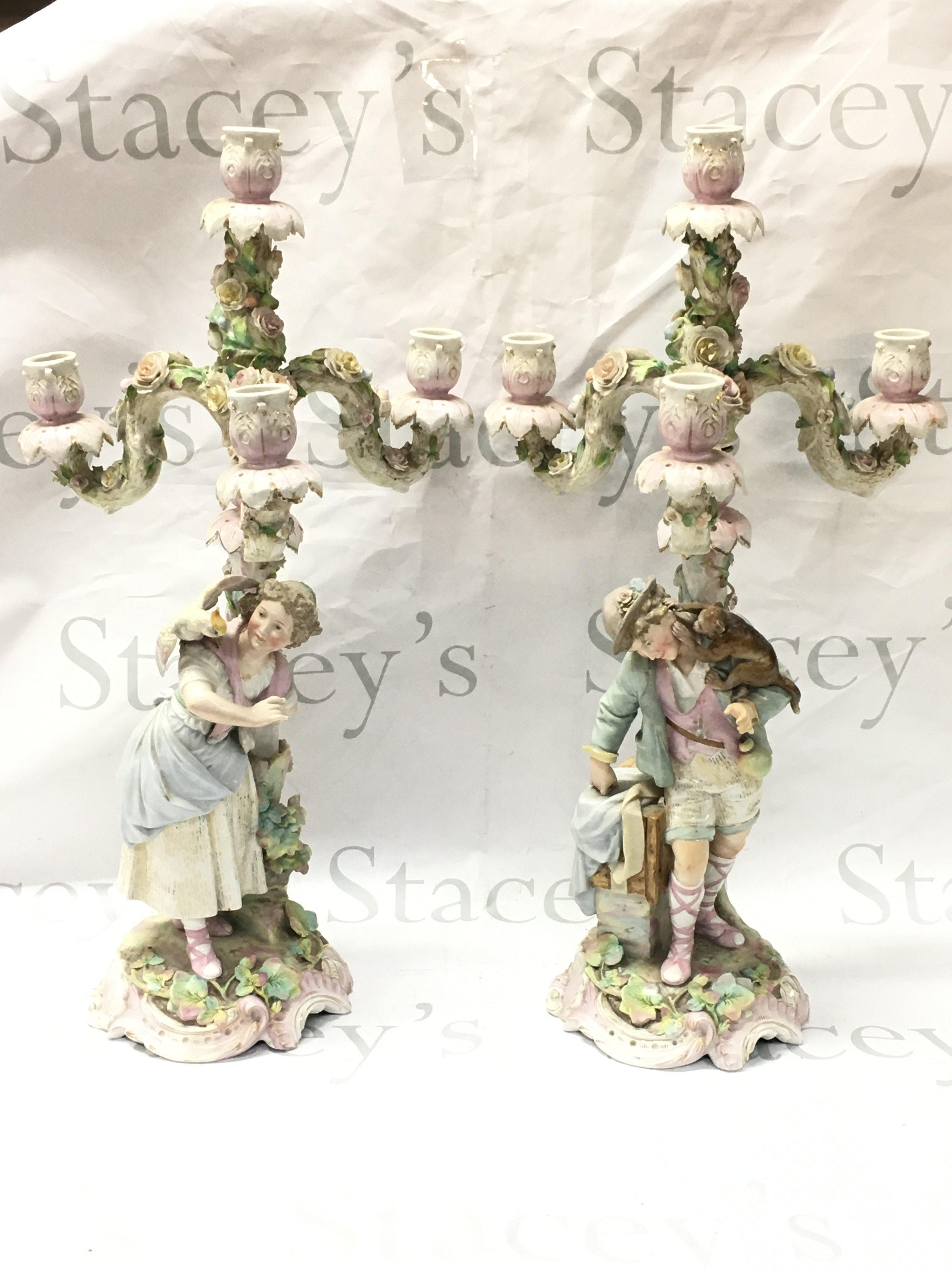 A pair of German porcelain candelabra couple figures with animals and floral decoration , 54cm tall . This lot cannot be posted