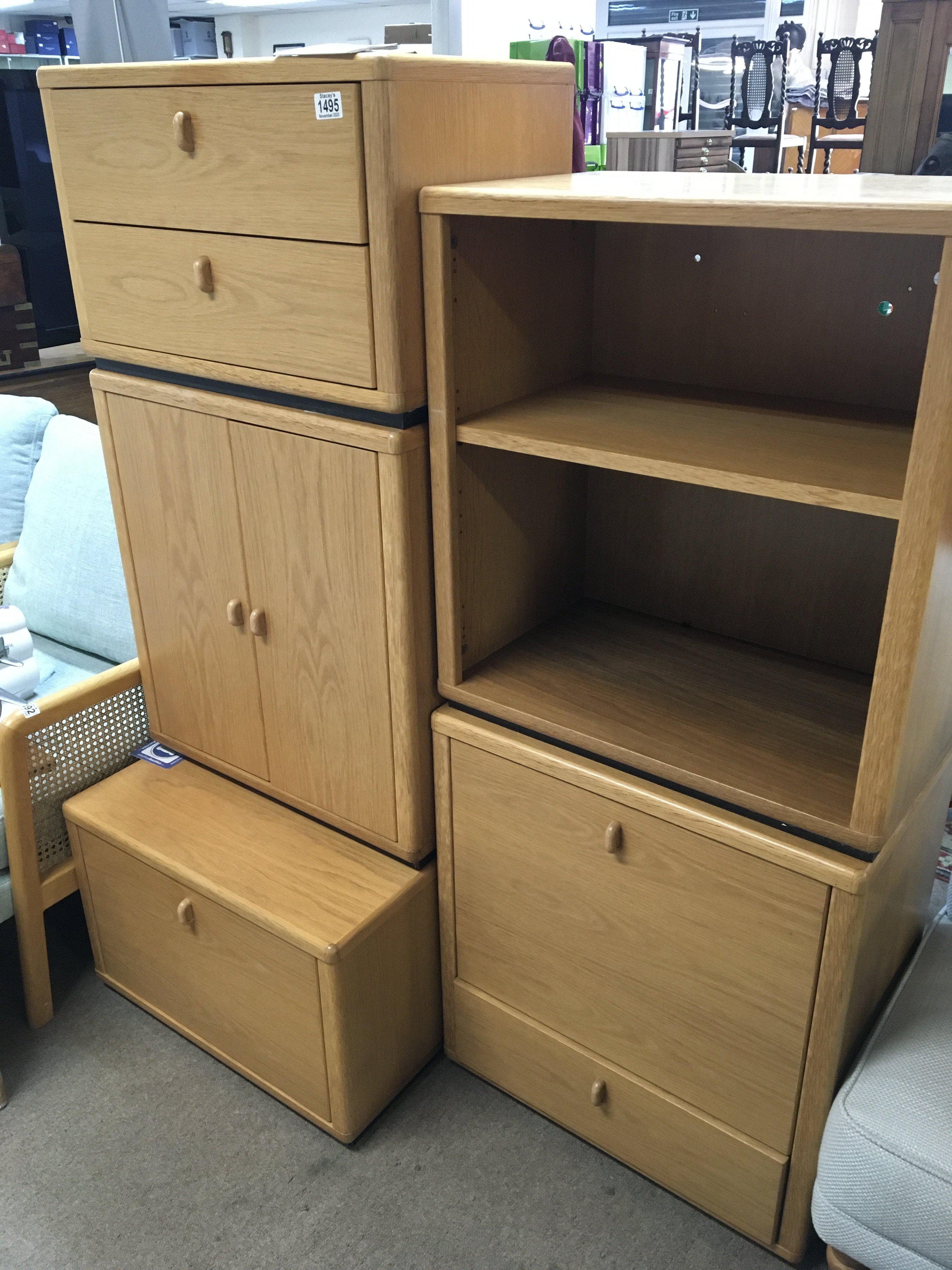 A modern design light oak open bookcase and conforming cabinets with drawers and cupboards.