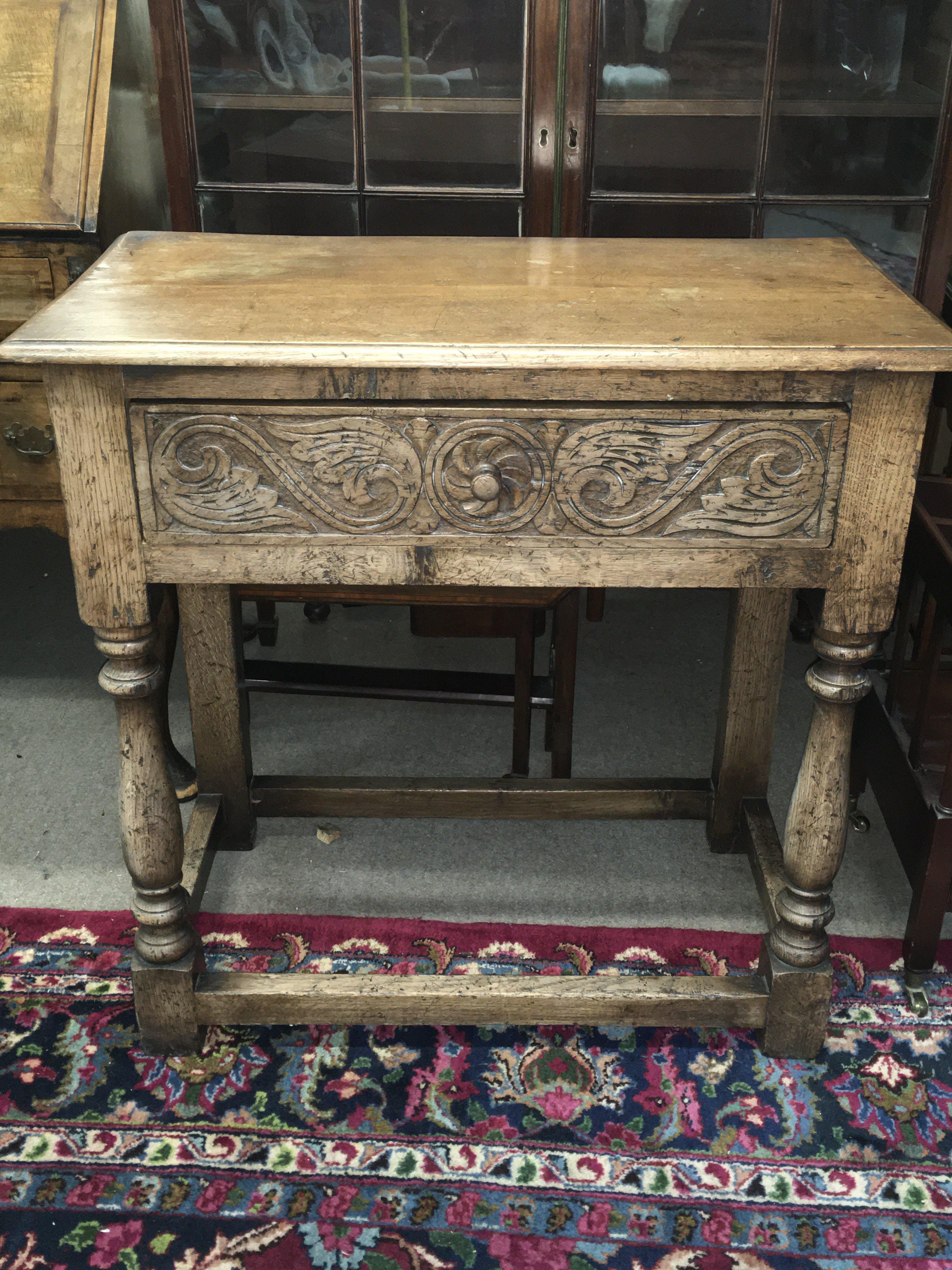 A carved oak side table with a single drawer . Dimensions 42cm deep 78cm wide 78cm tall.