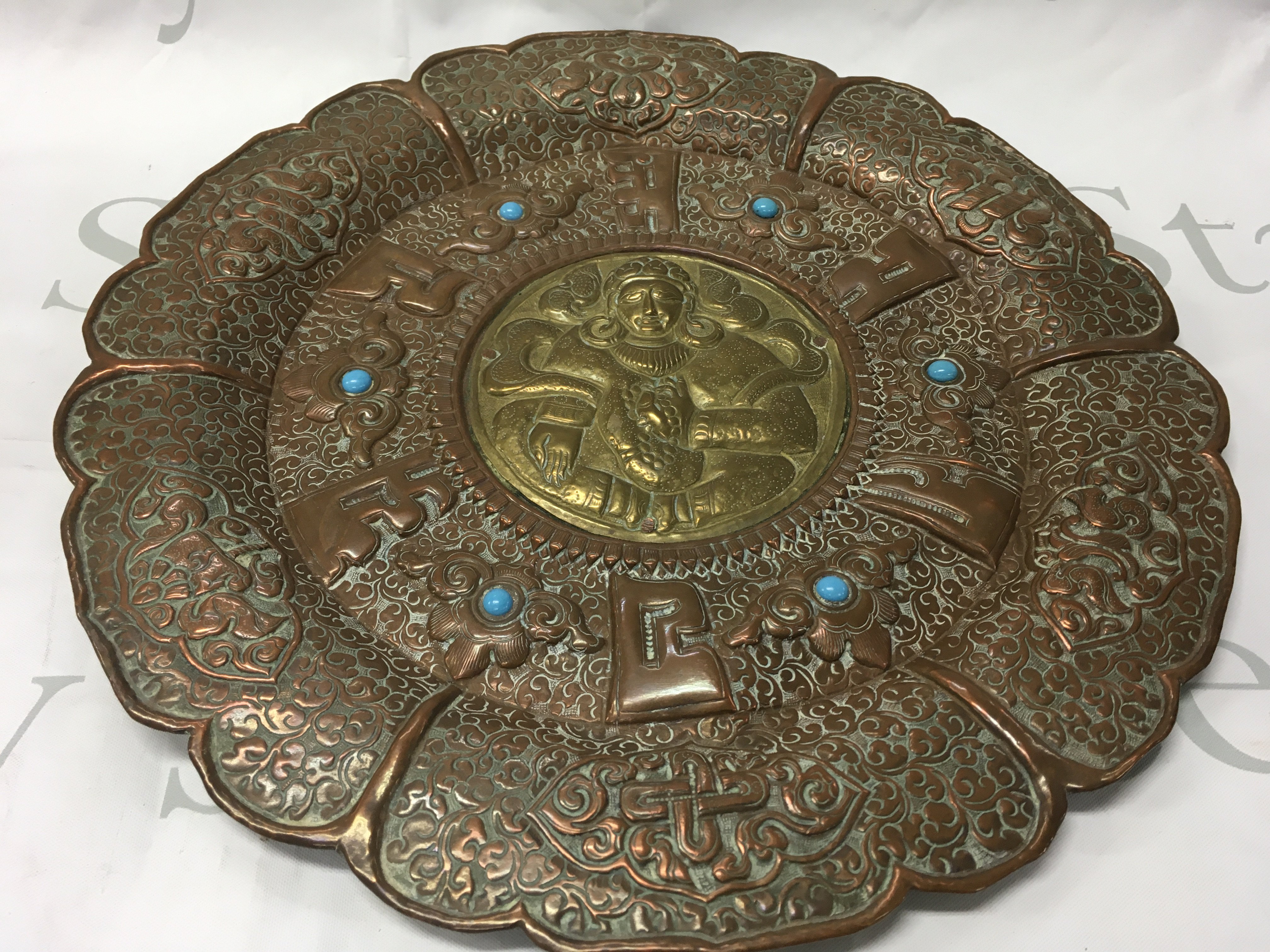 A Tibetan bodhisattva wall plaque inset with turquoise. Diameter 35cm.