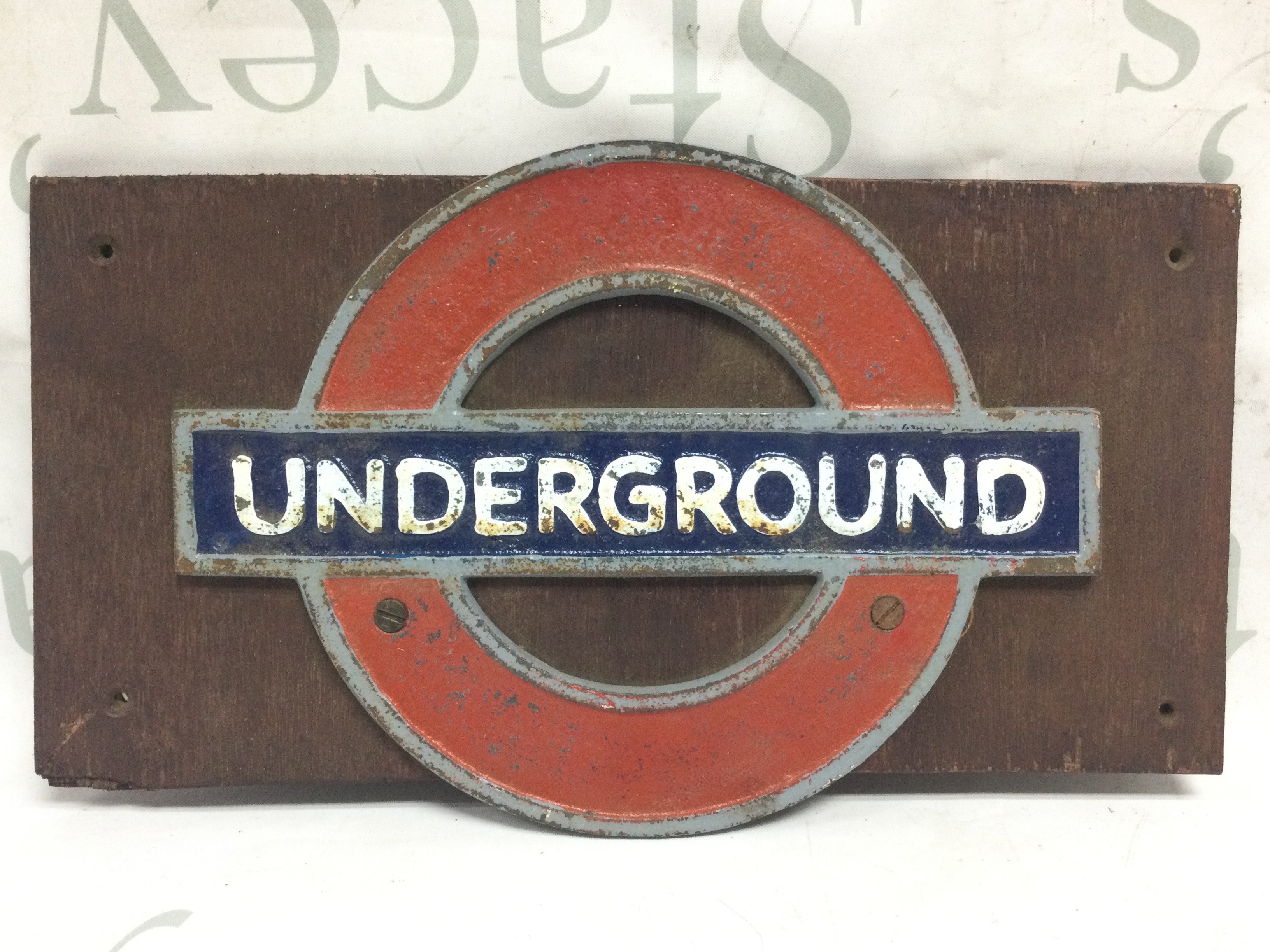 A small heavy metal sign for London Underground on wood , wood 35.5cm wide .