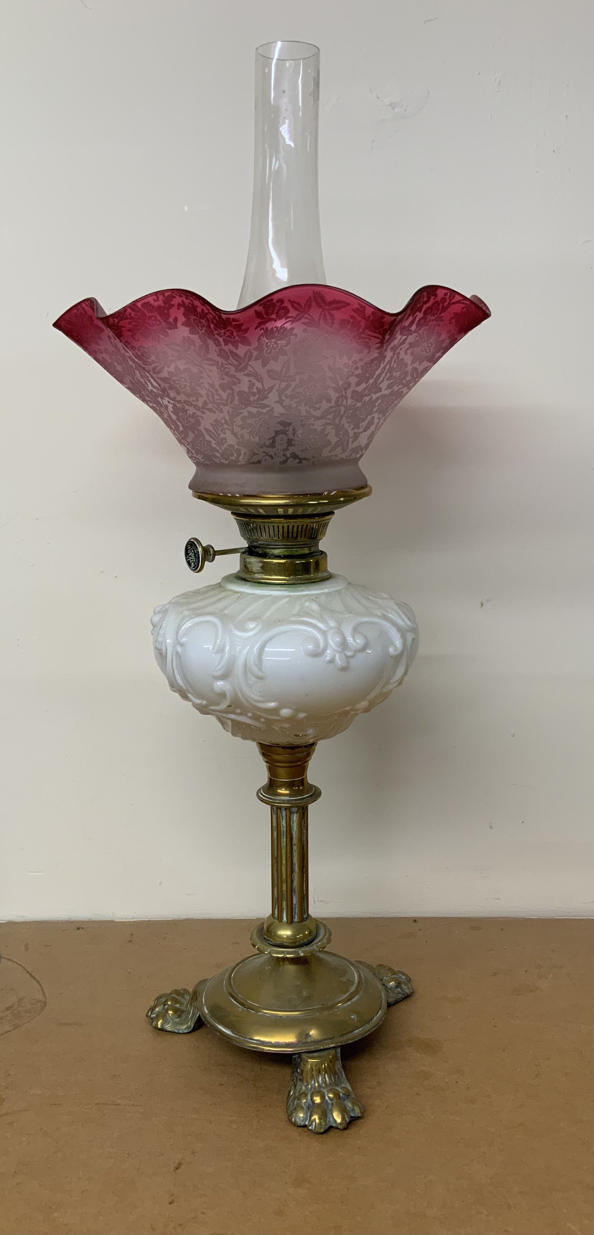 A Victorian brass footed oil lamp with cranberry etched shade.