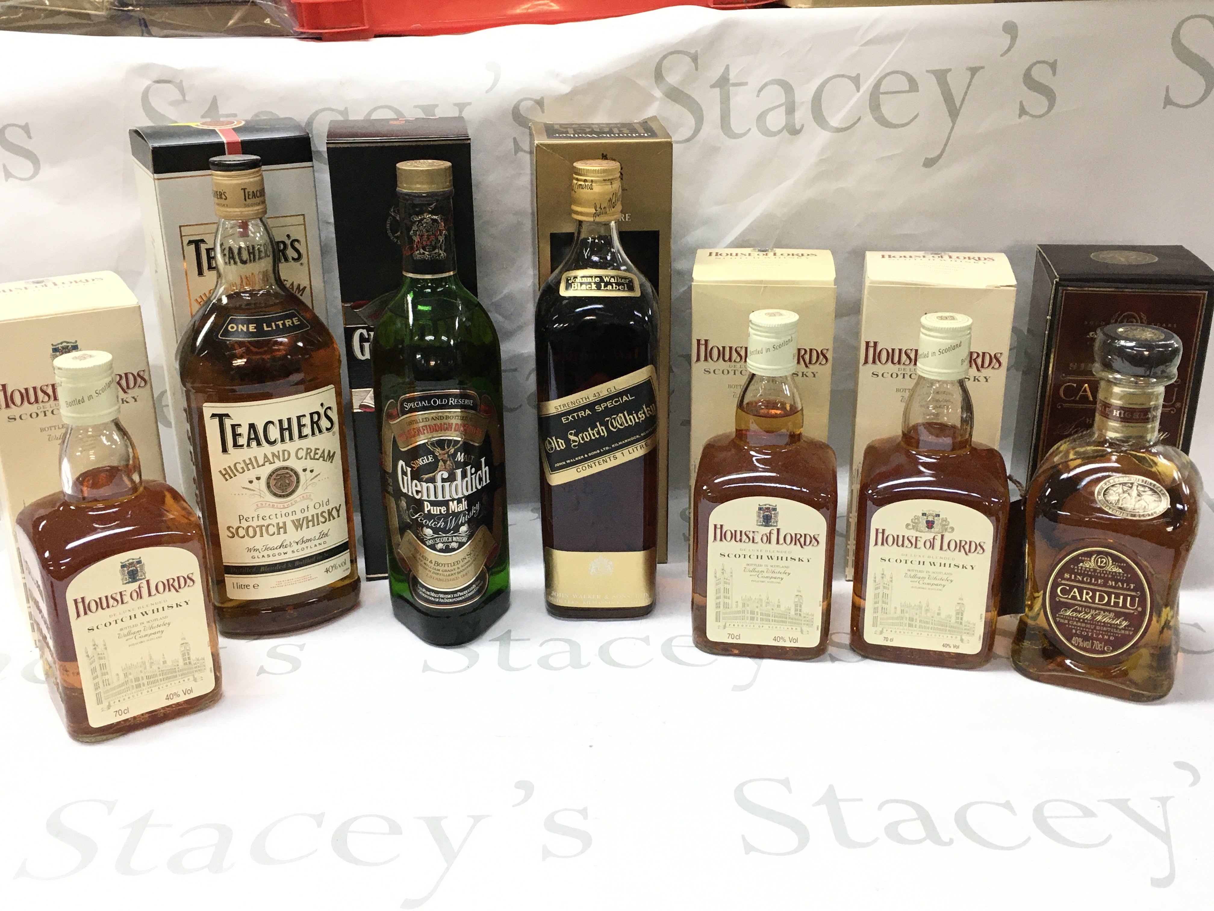A Collection of boxed whiskeys including House of Lords deluxe blended Scotch whiskey , Teachers Highland cream scotch, Glenfiddich pure malt scotch whiskey, Johnnie Walker black label extra special old scotch, Single malt Cardhu scotch