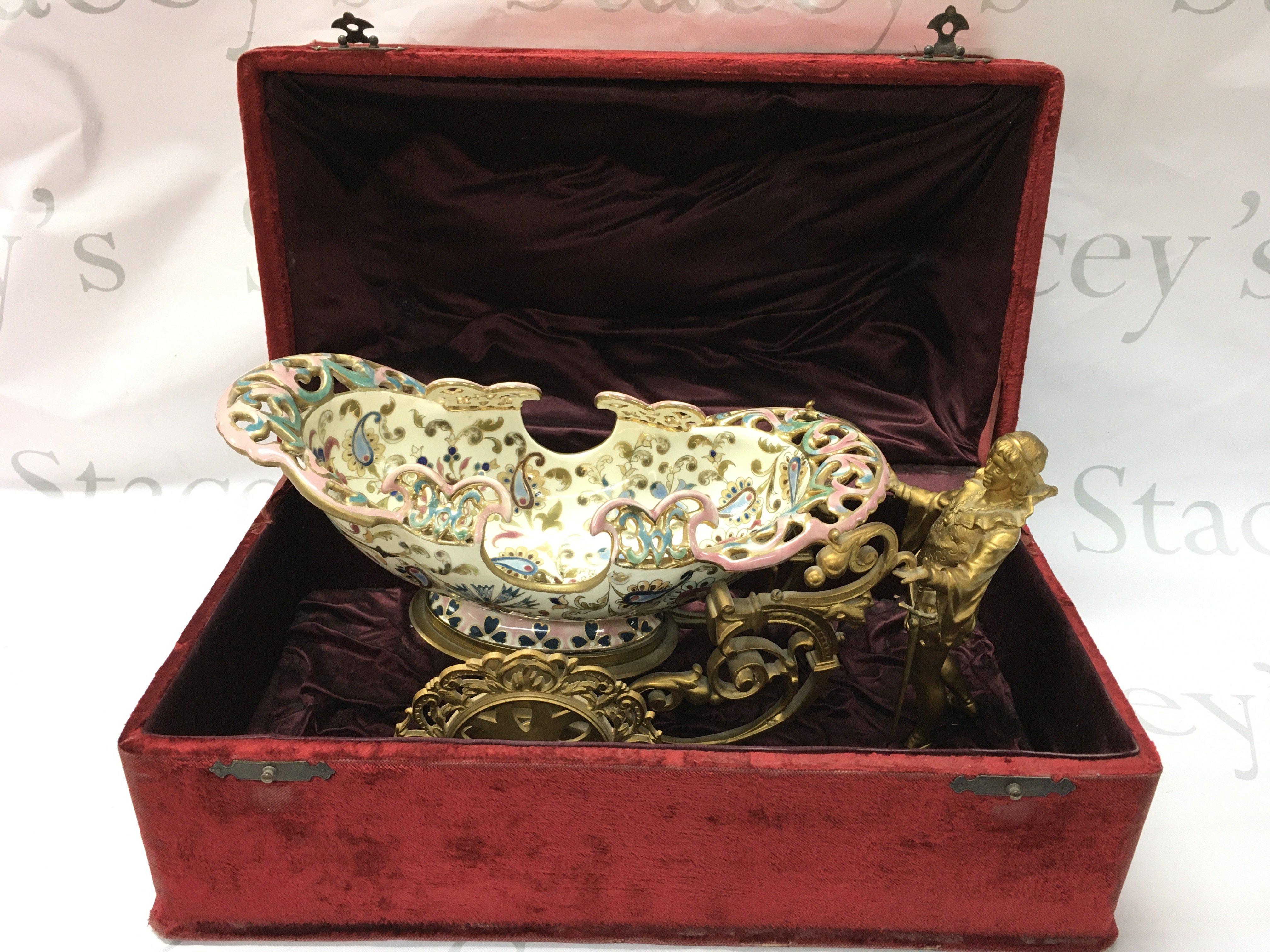 A carriage cachepot centrepiece bowl, gilted figure leading a boat shaped carriage with hand painted and gilted decoration and pierced border. Approximately 18cm tall 35cm long . Stored in a red velvet fitted case . This lot cannot be posted