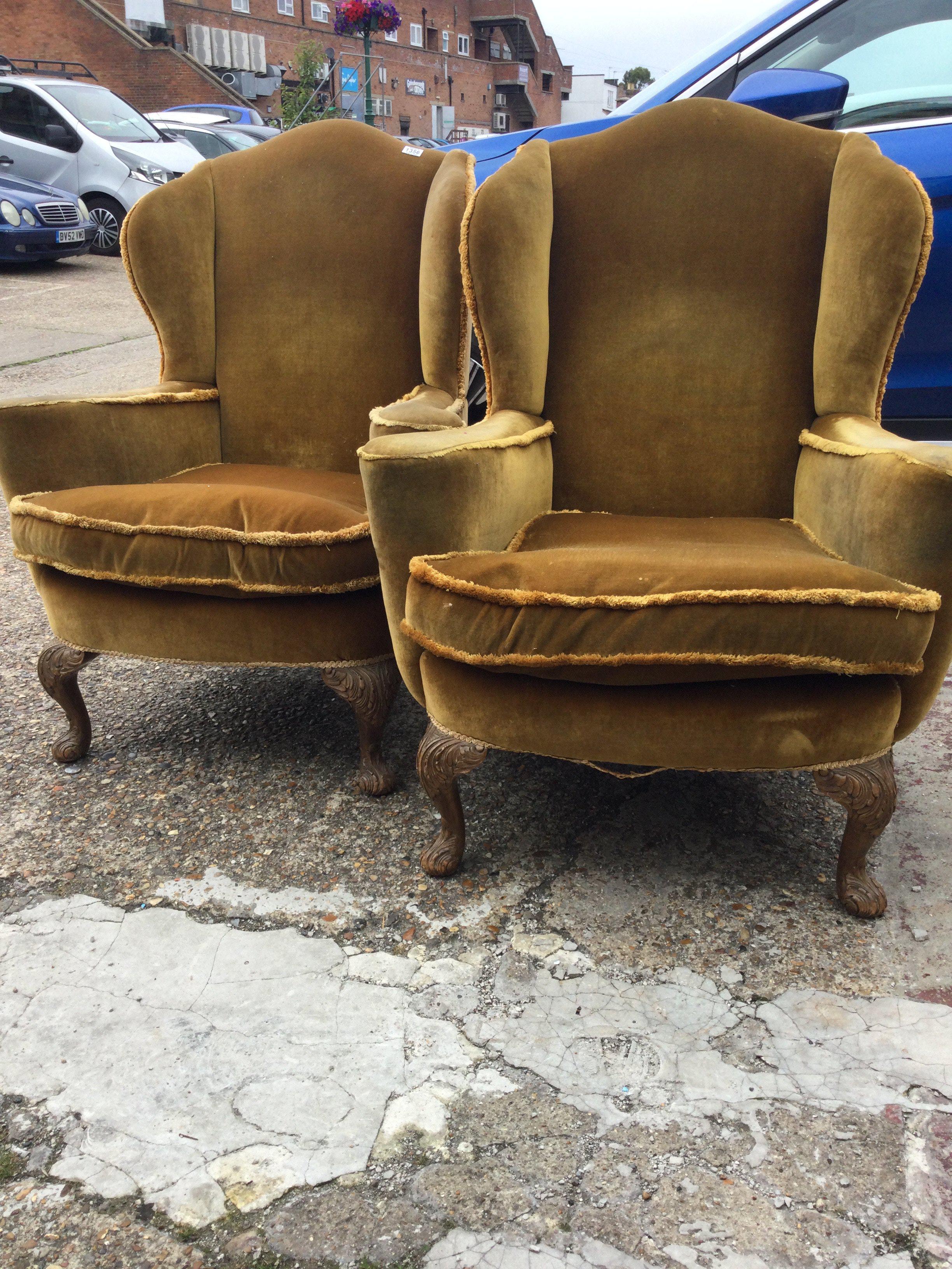 A pair of wing back open armchairs with carved cabriole legs .