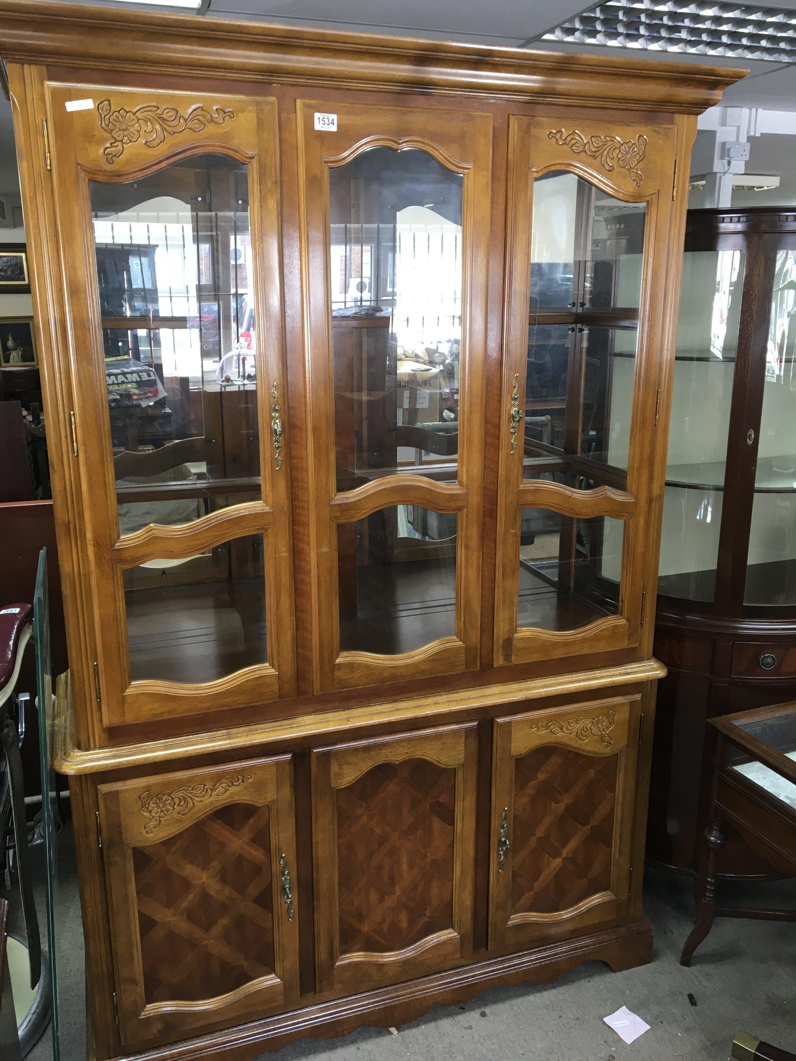 A light wood display cabinet with glazed doors above cupboards with glass shelves 202cm high width 135cm. (No reserve).