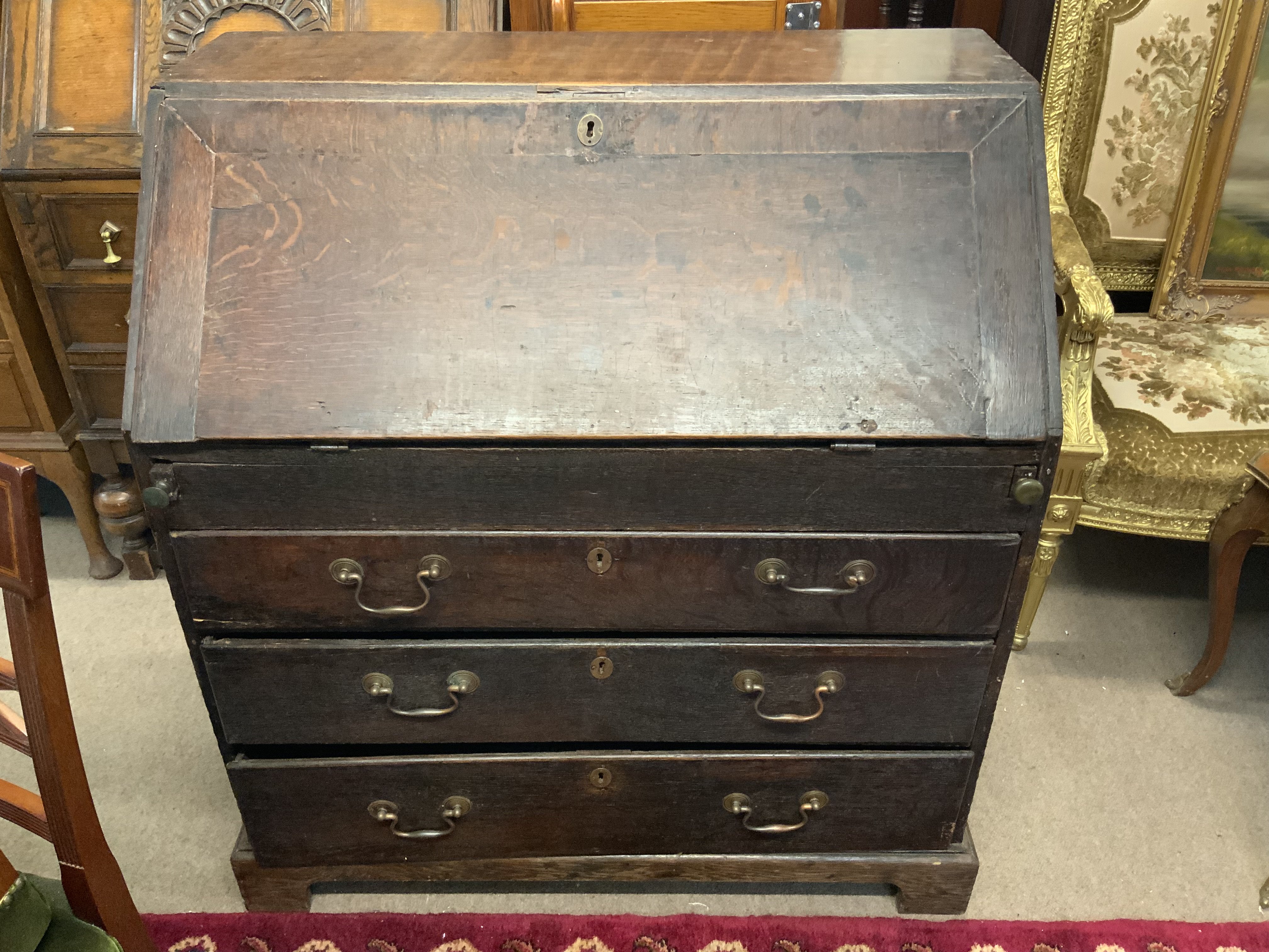 An antique oak Bureau, the fall front enclosing pigeonhole and drawer interior, above four long graduated drawers and raised on bracket feet. 90cm x 100cm