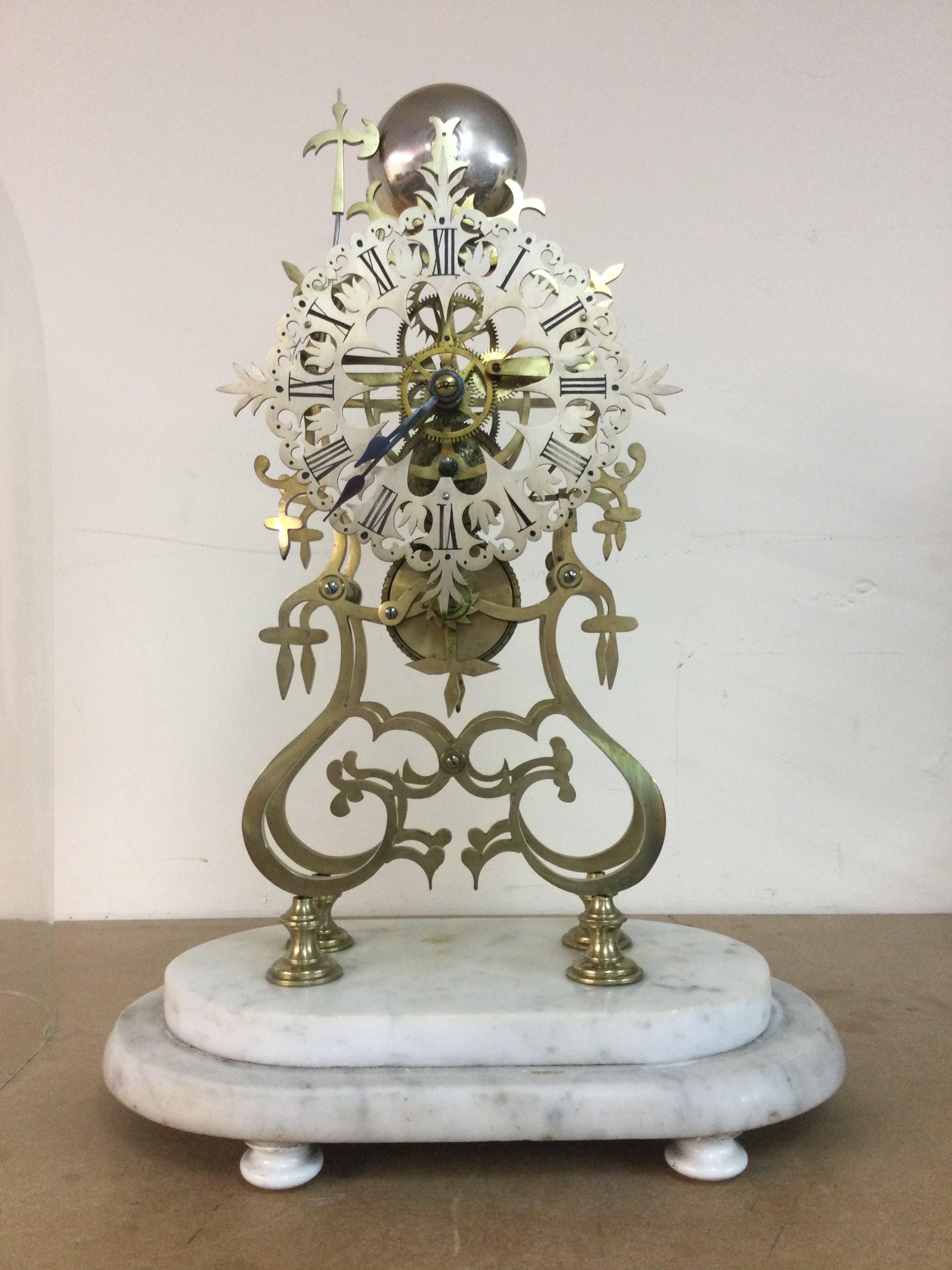 A Victorian brass skeleton clock striking on a bell under glass dome on marble base . 48 cm With key and pendulum.