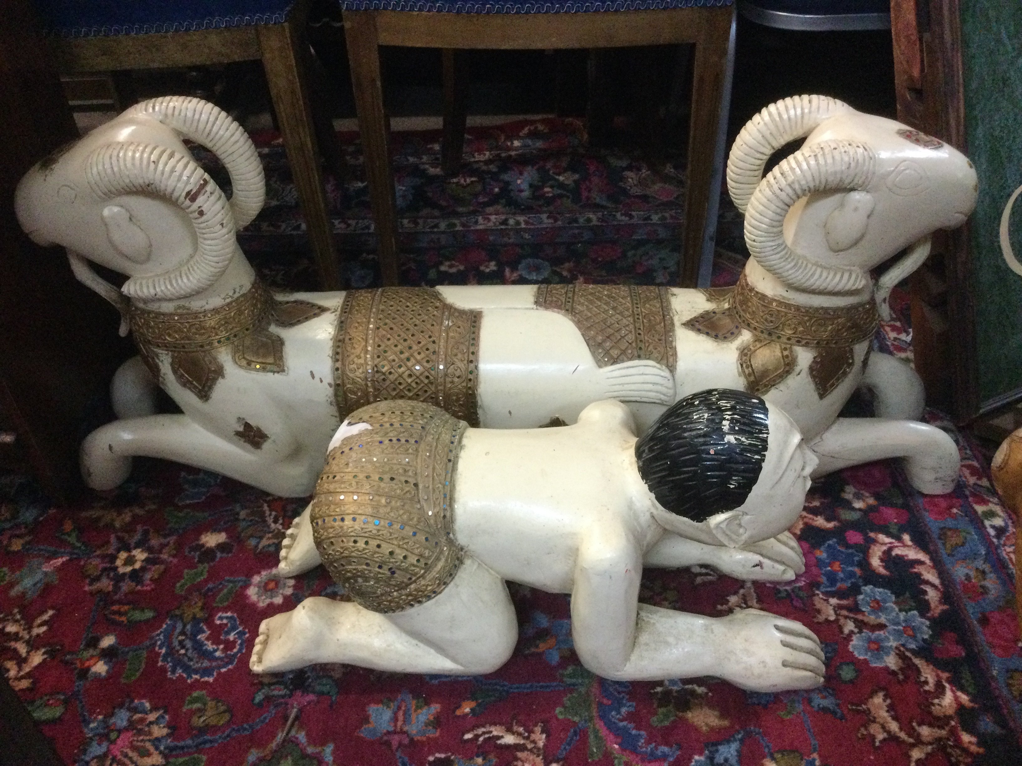 A wooden painted Indian foot rest of a two headed mythical beast, approx length 93cm plus one other in the form of a recumbent male figure, approx length 55cm. Shipping category D.