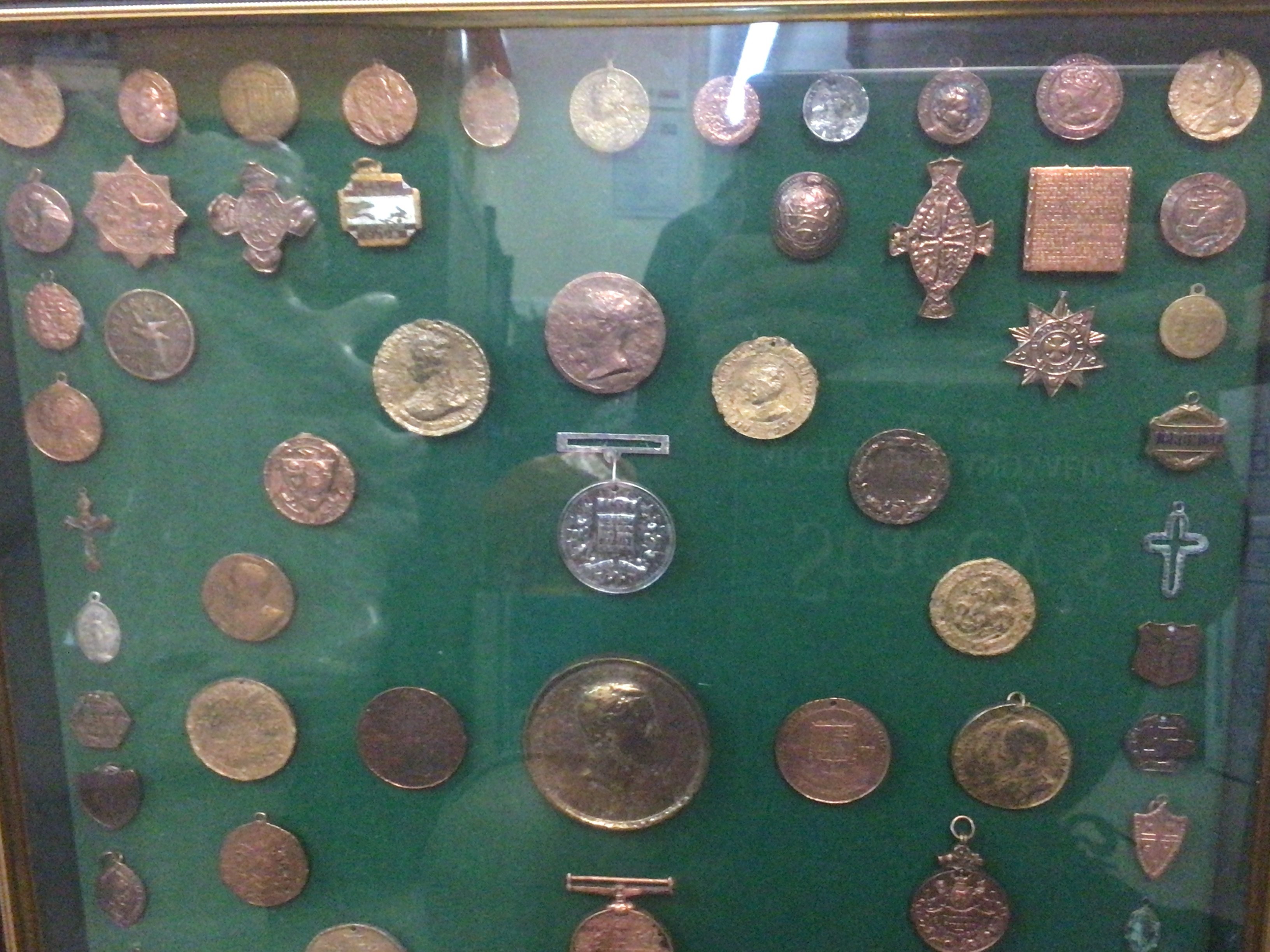 A case containing military medals, badges, coins and tokens . This lot cannot be posted