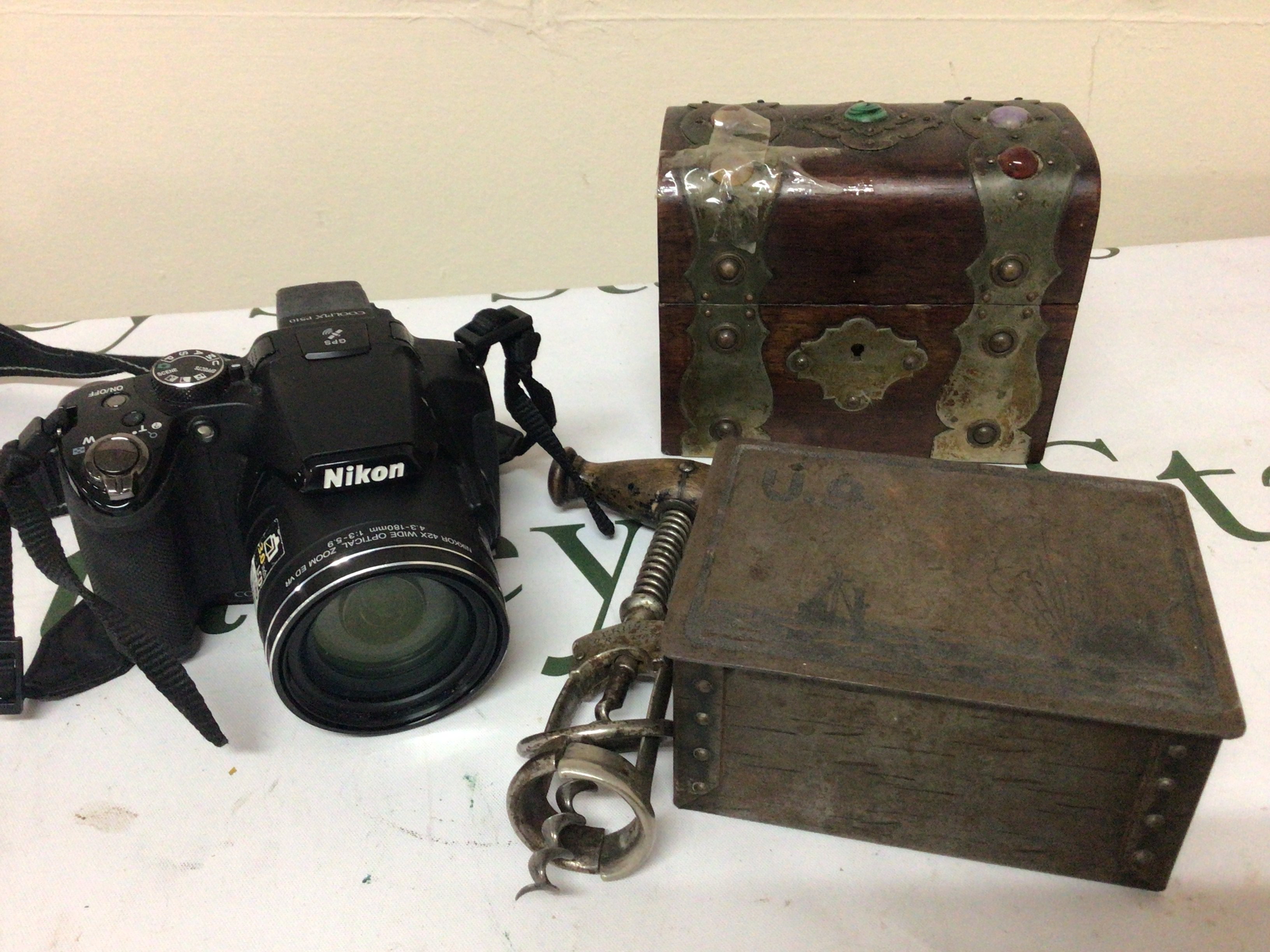A collection of items comprising a Nikon Camera small metal bound casket Vintage corkscrew and a tin U9 sinking a battle Ship. (4)