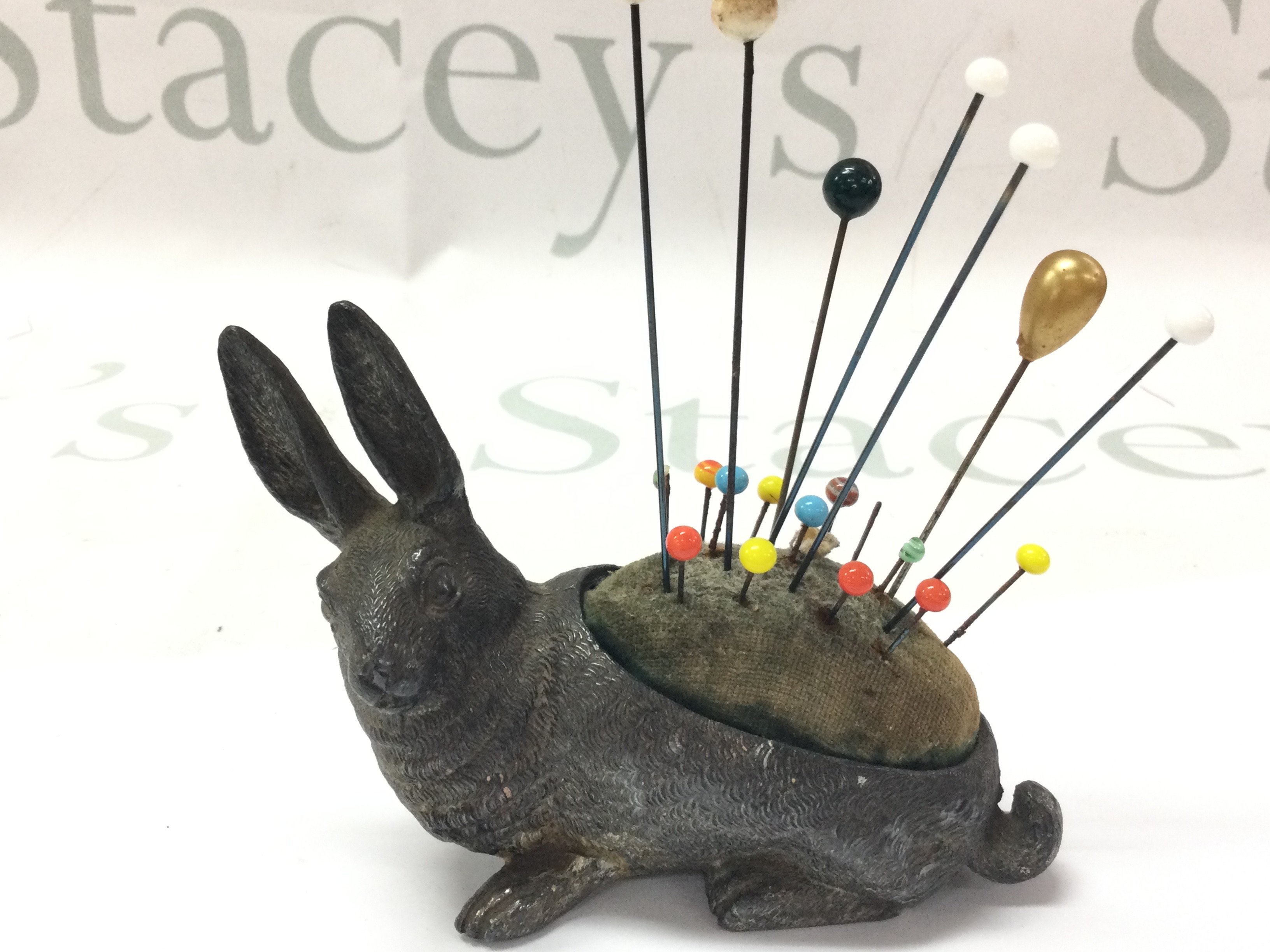 A small Victorian figure of a hare as a hat pin stand 8cm tall, 11Cm wide.