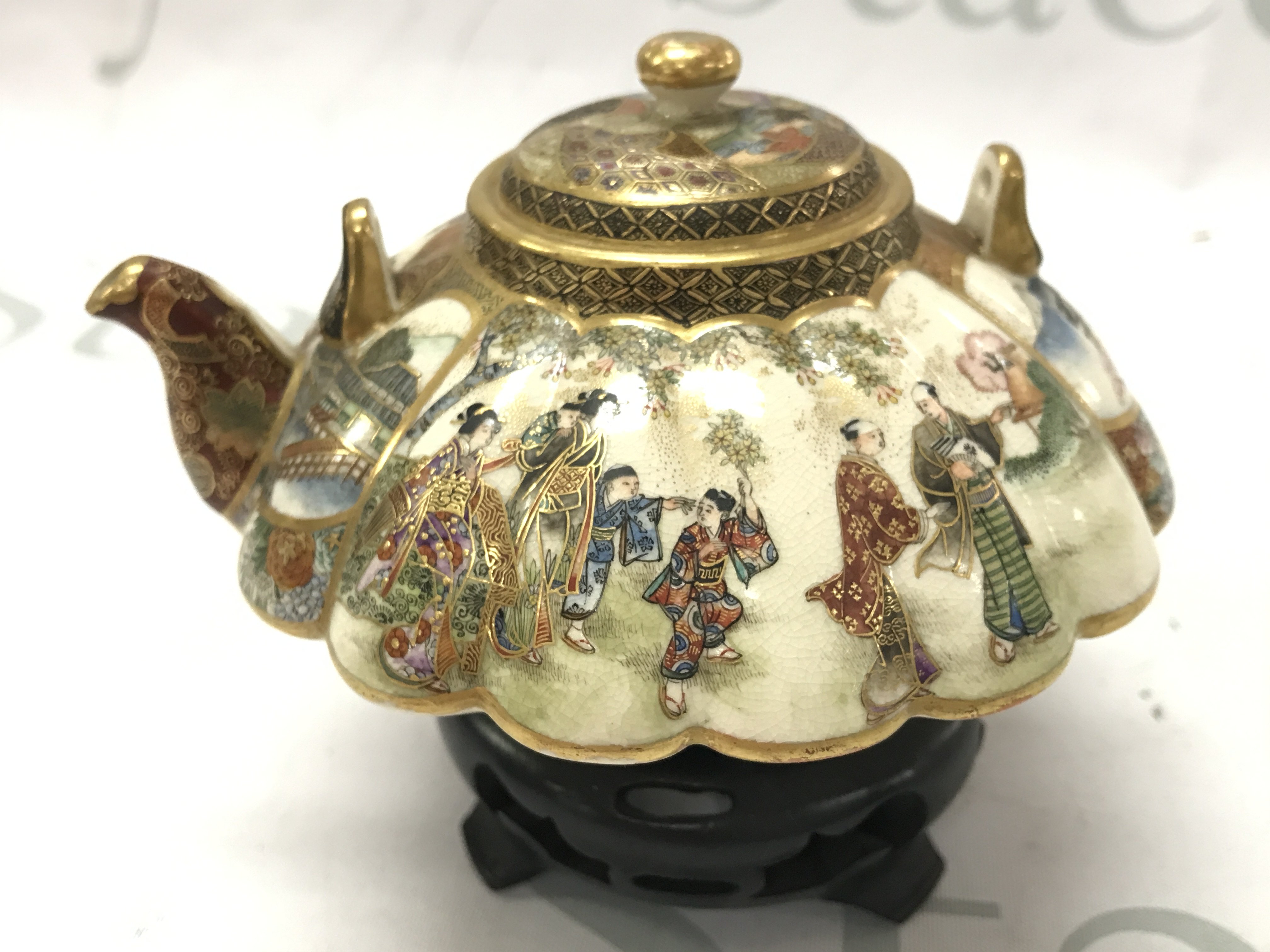 A 19th century Japanese satsuma tea pot decorated with gilt and a figural , temple scene. No damage or restoration . With wooden base. This lot cannot be posted