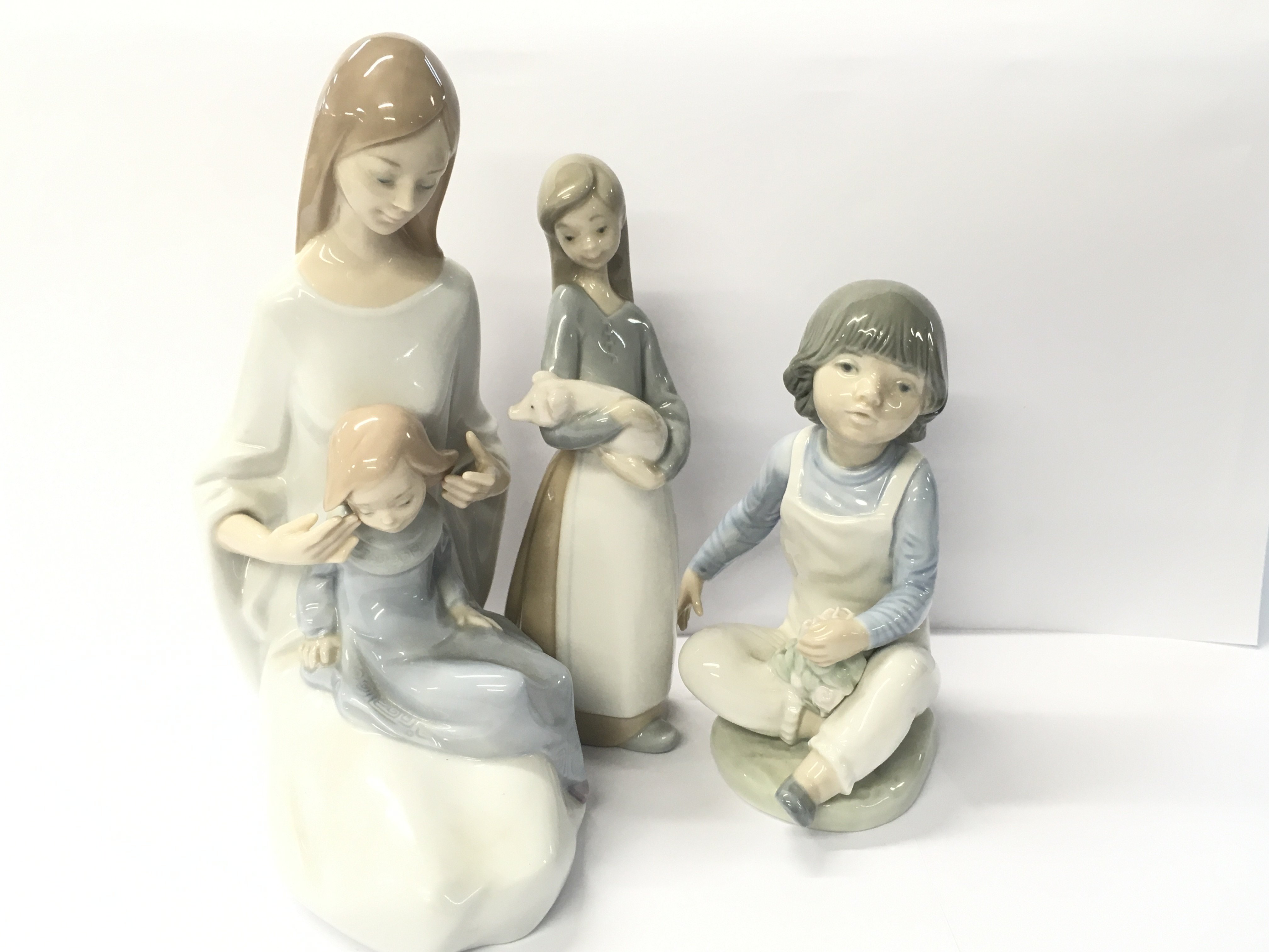 Five Spanish-made ceramic figures, four of which are NAO and one made by Lladro.