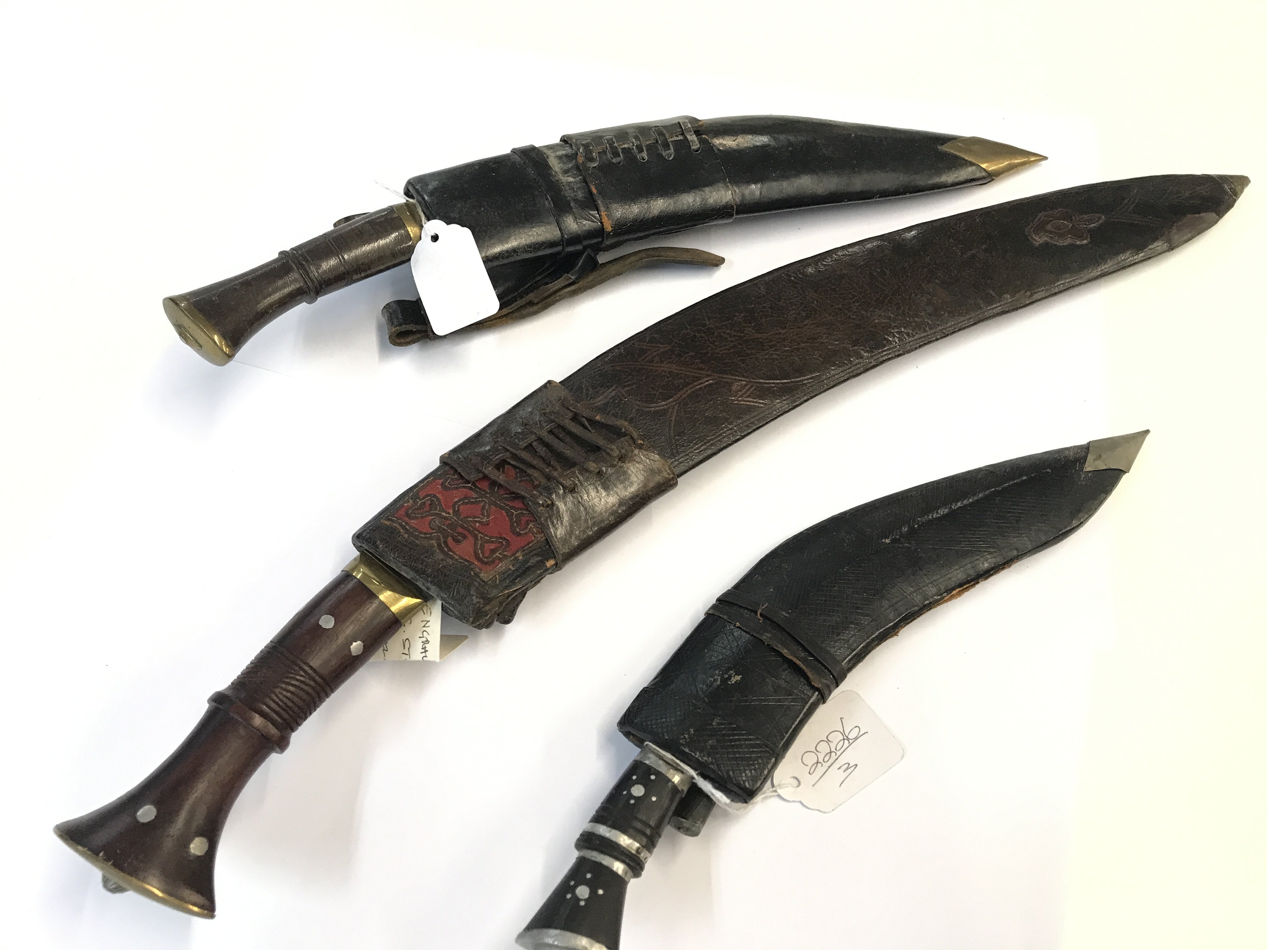 Three Early 20th Century Kukri Knifes The Traditional Nepalese knife. With brass set wood and horn handles including a smaller example (3)