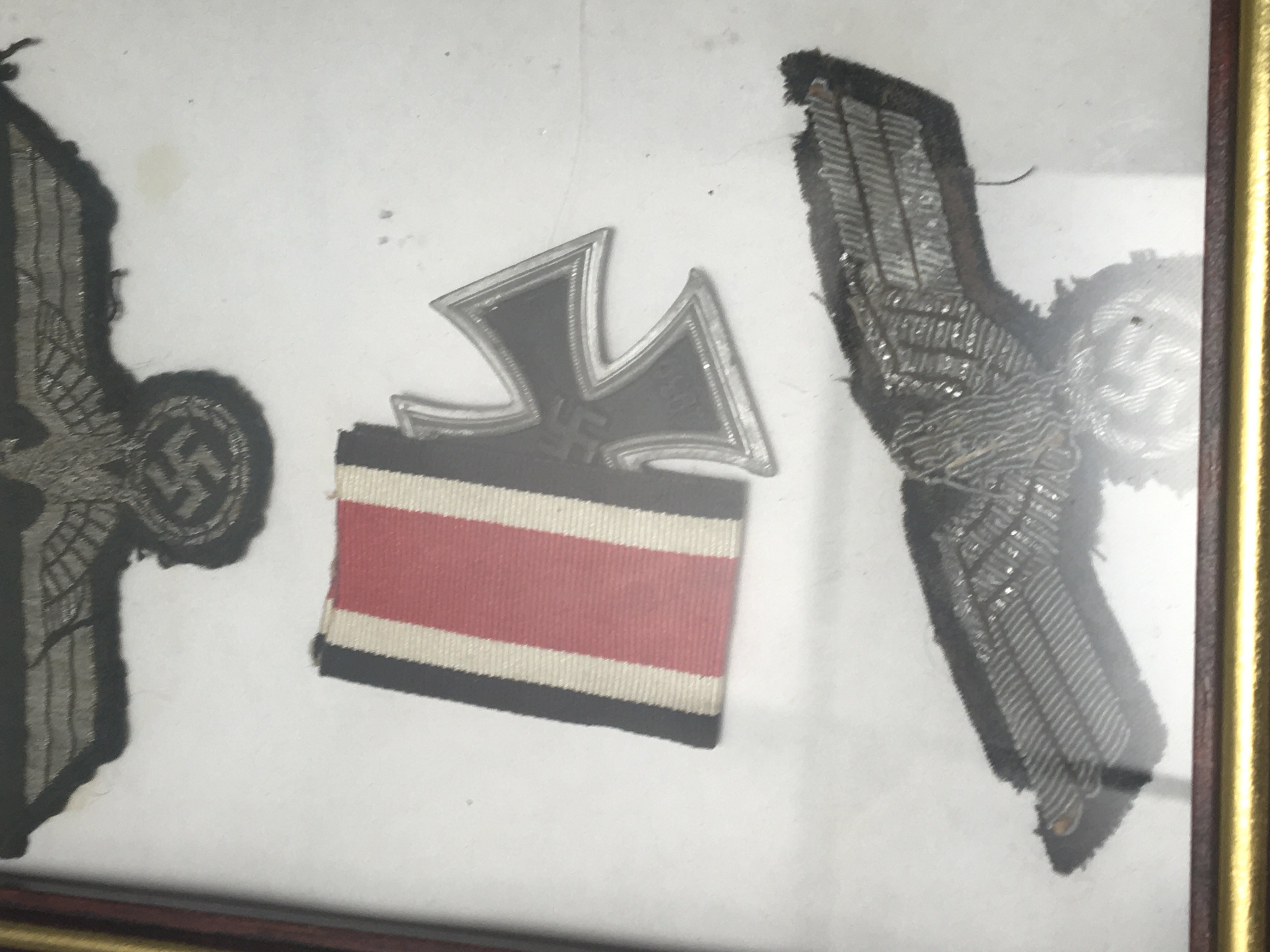 A German Third Reich SS Officers cloth badge an Afrika Corps cloth badge and a retrospective Iron cross in a modern frame.