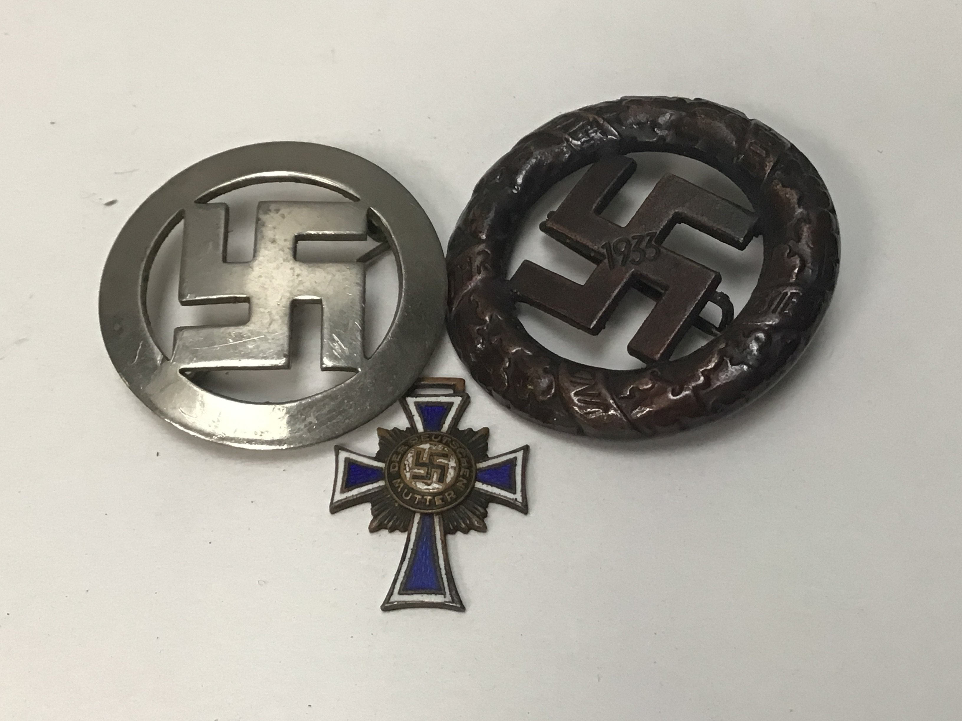 A rare 1933 German Political rally badge 1933 the reverse w with makers marks Deschler & Sohn, Munchen a miniature enamel mother cross and one other badge (3)