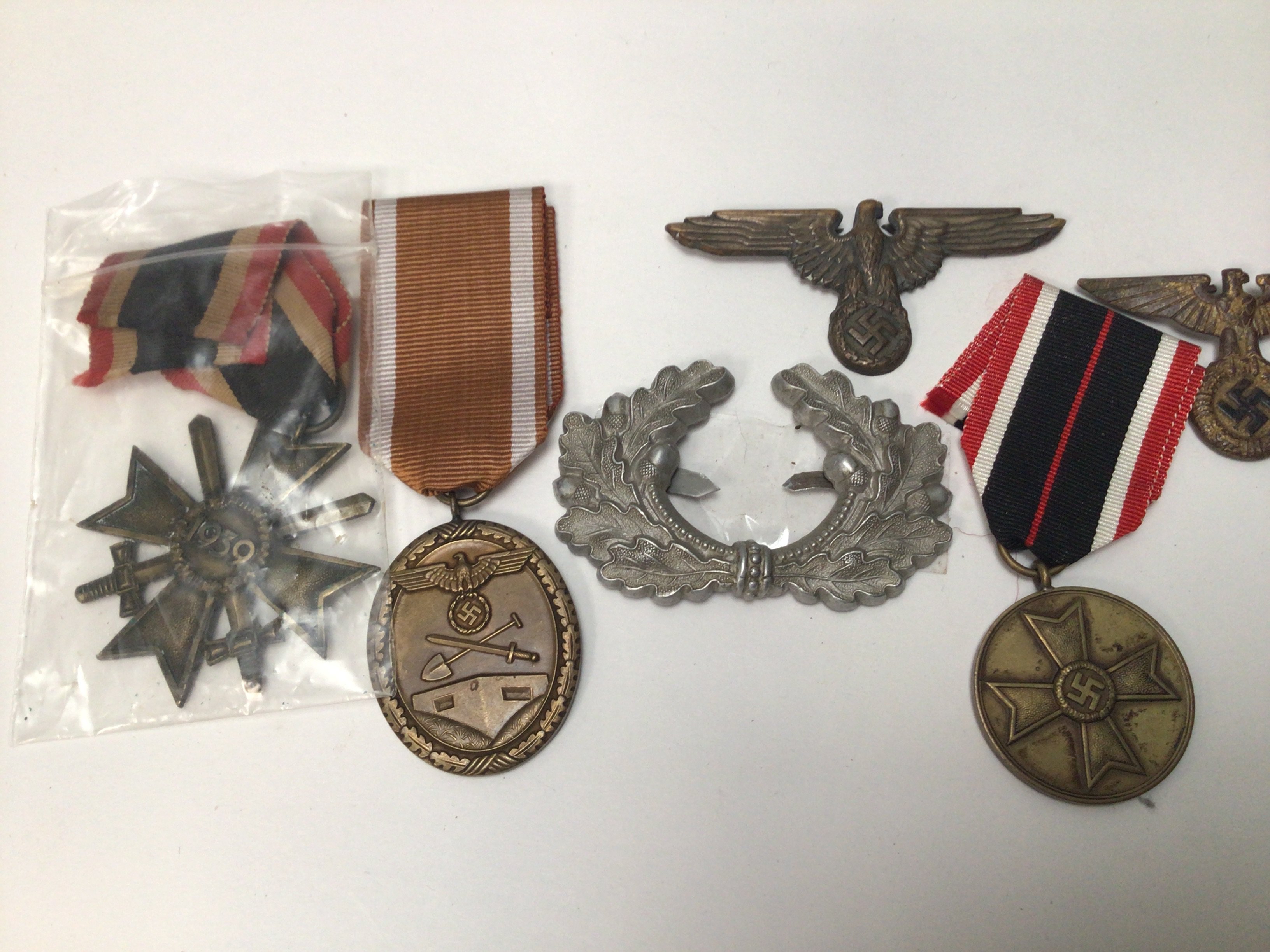 A collection of German Third Reich II world war medals and badges a Civilian war merit medal A West Wall medal A second class war merit medal and two other badges.