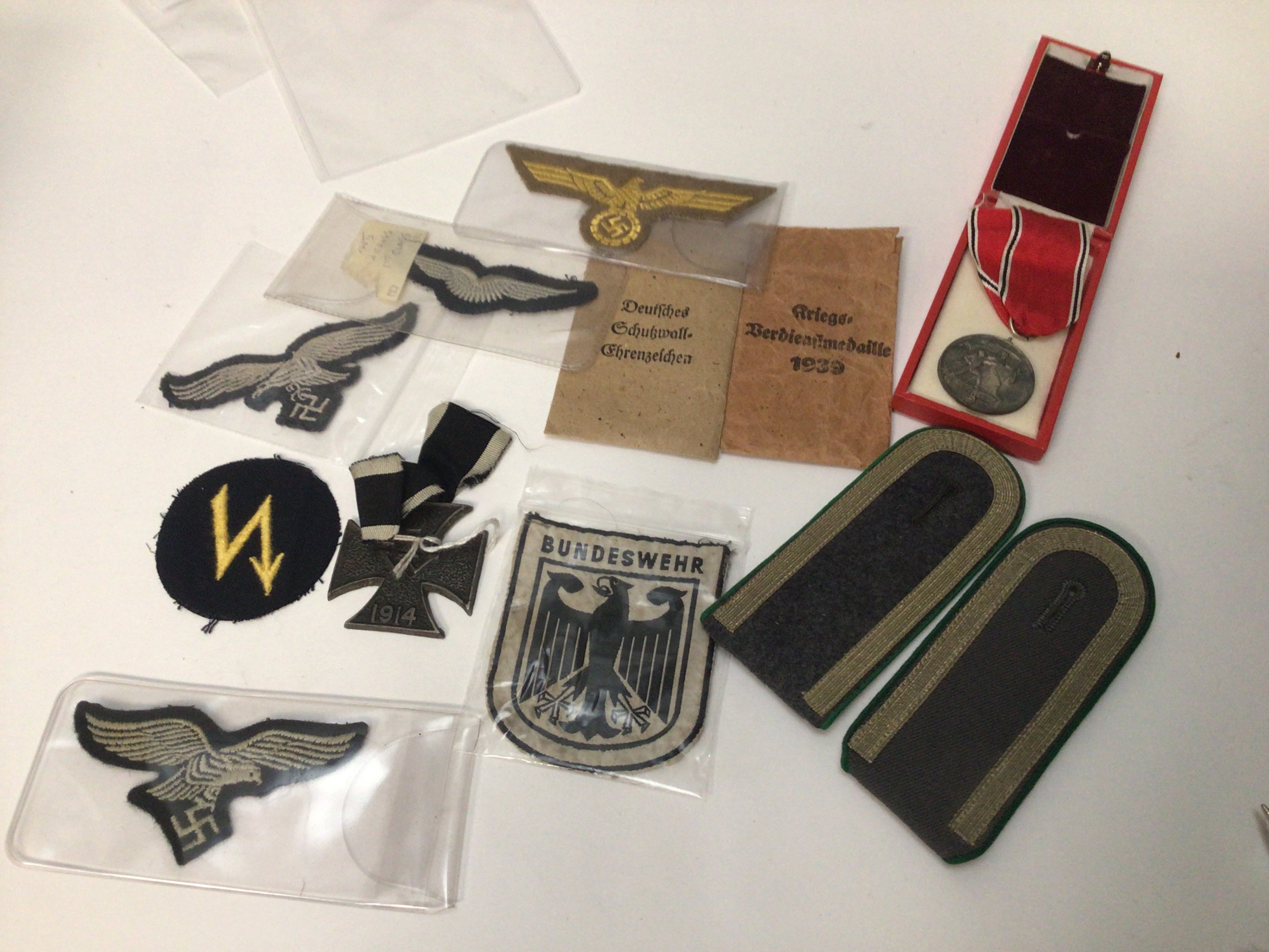 A 1914 steel cross German Third Reich cloth badges two envelopes no contents a civilian medal and a pair of officers epaulets