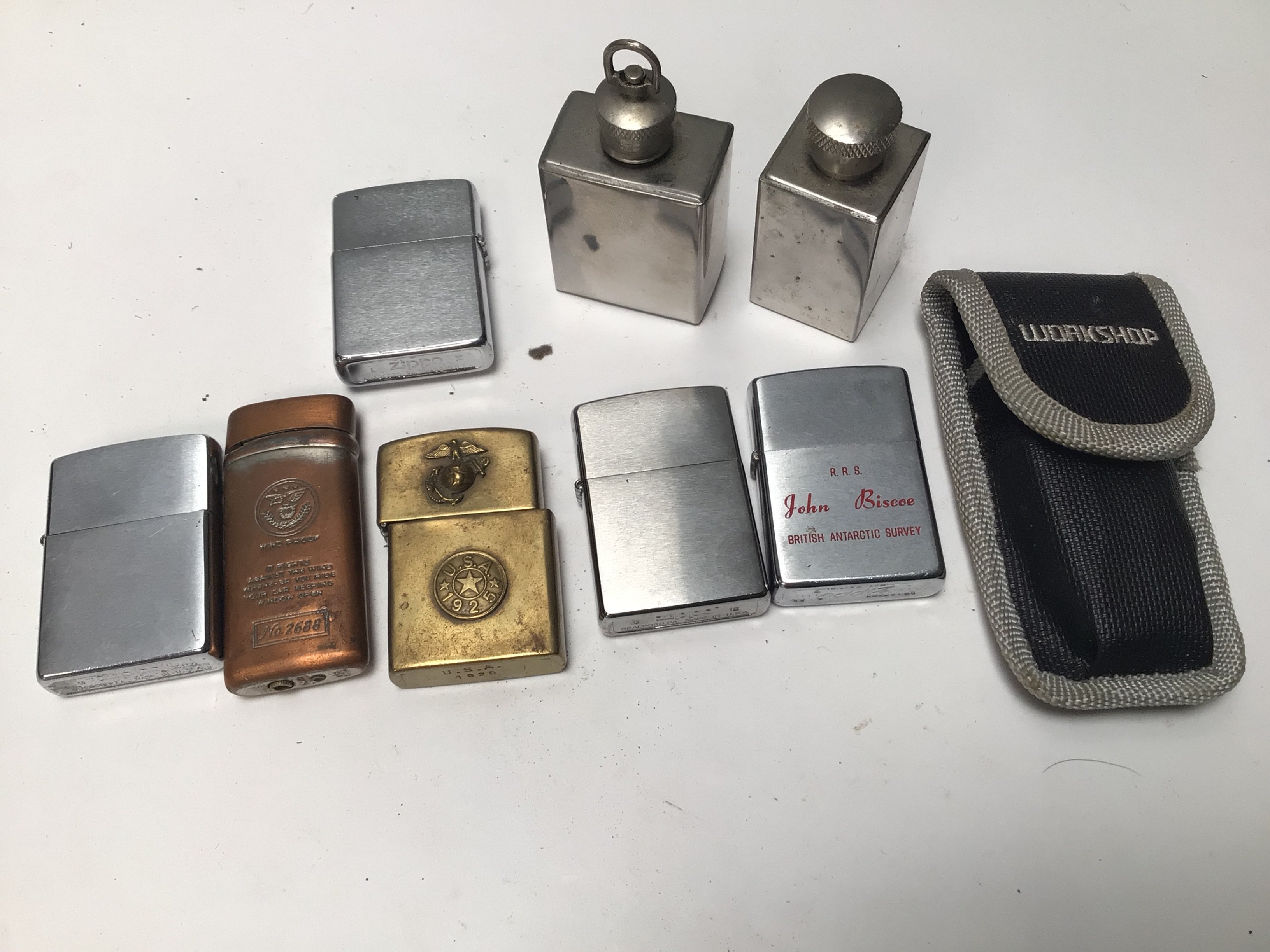 A collection of Zipo type lighters including a brass lighter with USA 1925 raised emblem.
