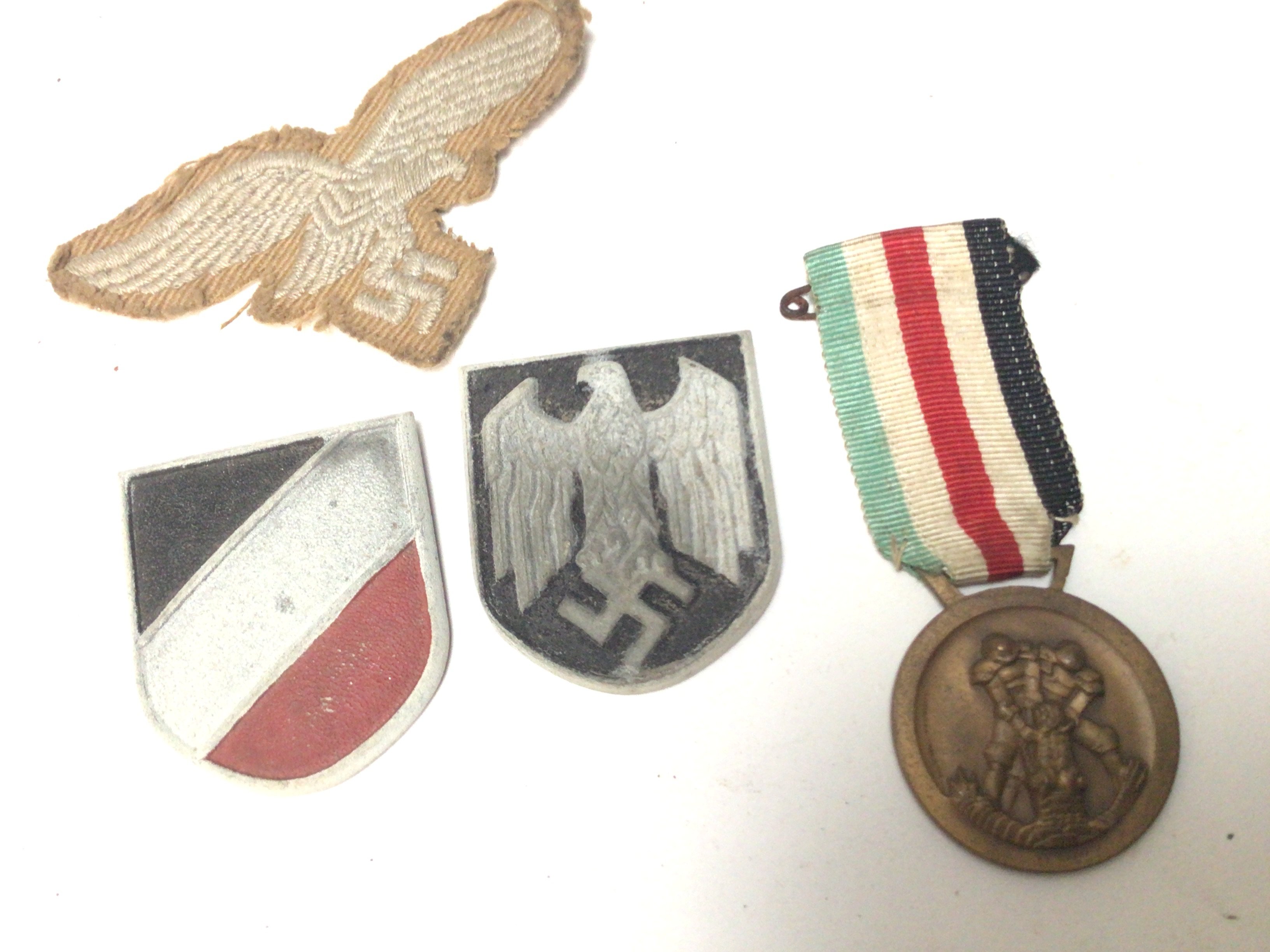 A German Third Reich Afrika Korps service medal cloth badge and metal badges.