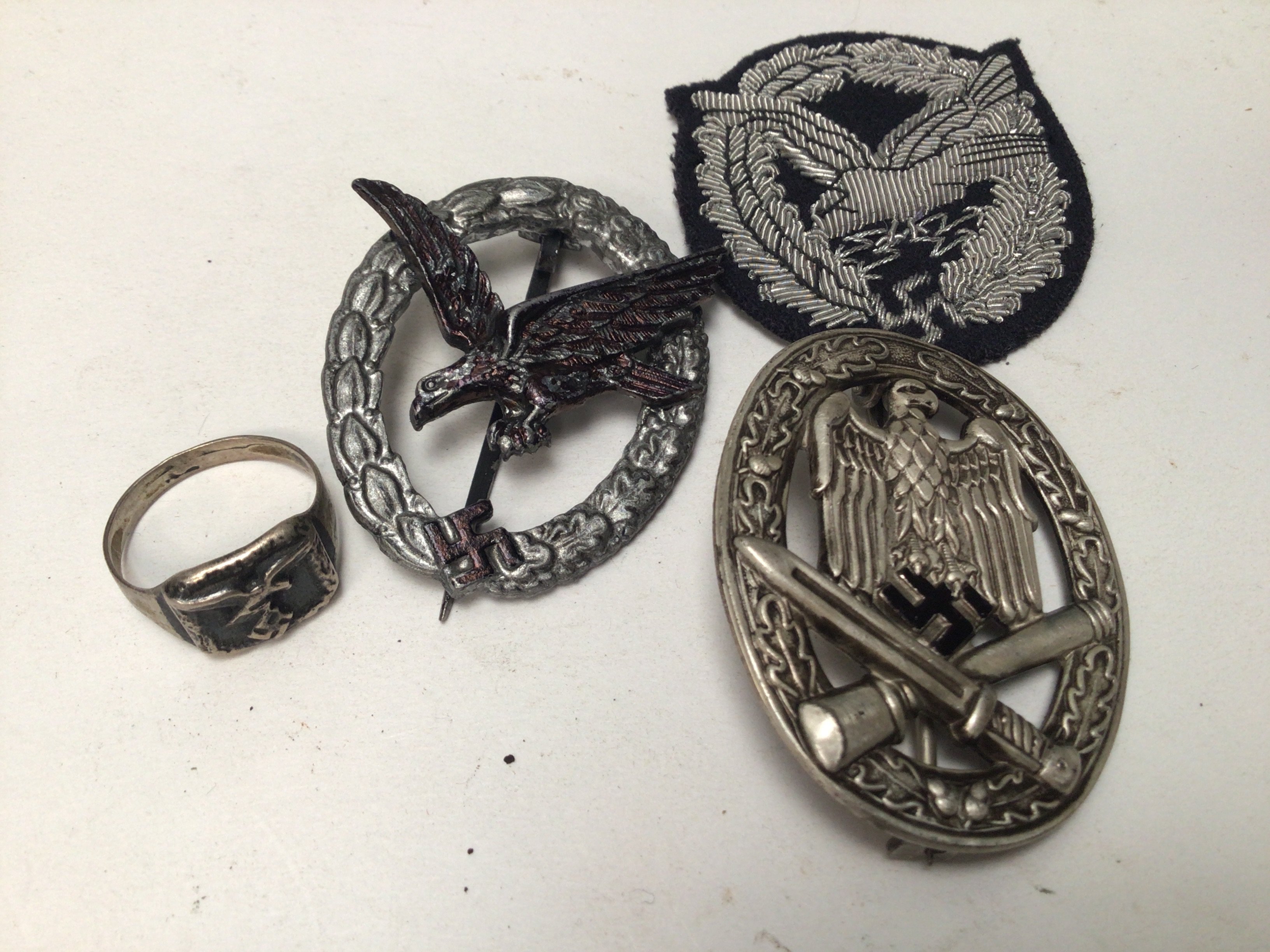A German Third Reich Luftwaffe Radio operators badge (possibly retrospective copy) and a silver Luftwaffe ring a pressed metal Assault Badge and cloth badge (4)